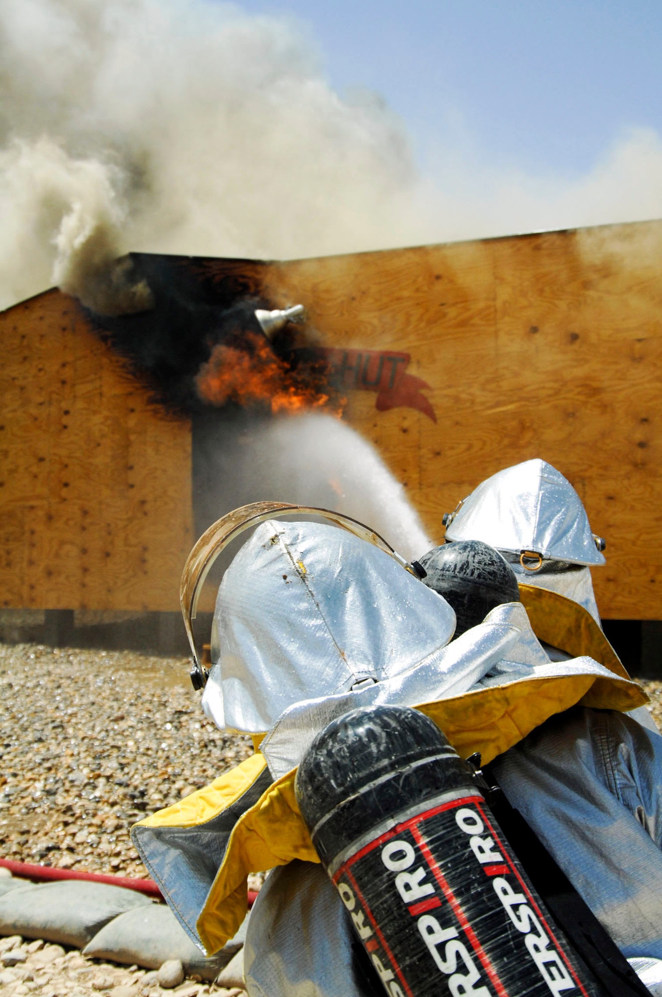 Two firefighters perform an exterior attack on a fire in the Army Motor Pool June 19 on Camp Adder, Iraq. Due to munitions contained in the building and no potential for loss of life, the firefighters switched to defensive operations for the blaze using six trucks to keep it under control and confined to the building. The firefighters are from the 407th Expeditionary Civil Engineer Squadron at Ali Air Base, Iraq. (U.S. Air Force photo/Master Sgt. Robert W. Valenca) 