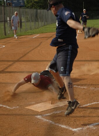 Jesse Fry, 437th LRS, jumps to catch the ball as Todd Grabic, Security Forces Detachment 3, slides under him to score a run Tuesday.  (U.S. Air Force photo/ Staff Sgt. April Quintanilla)