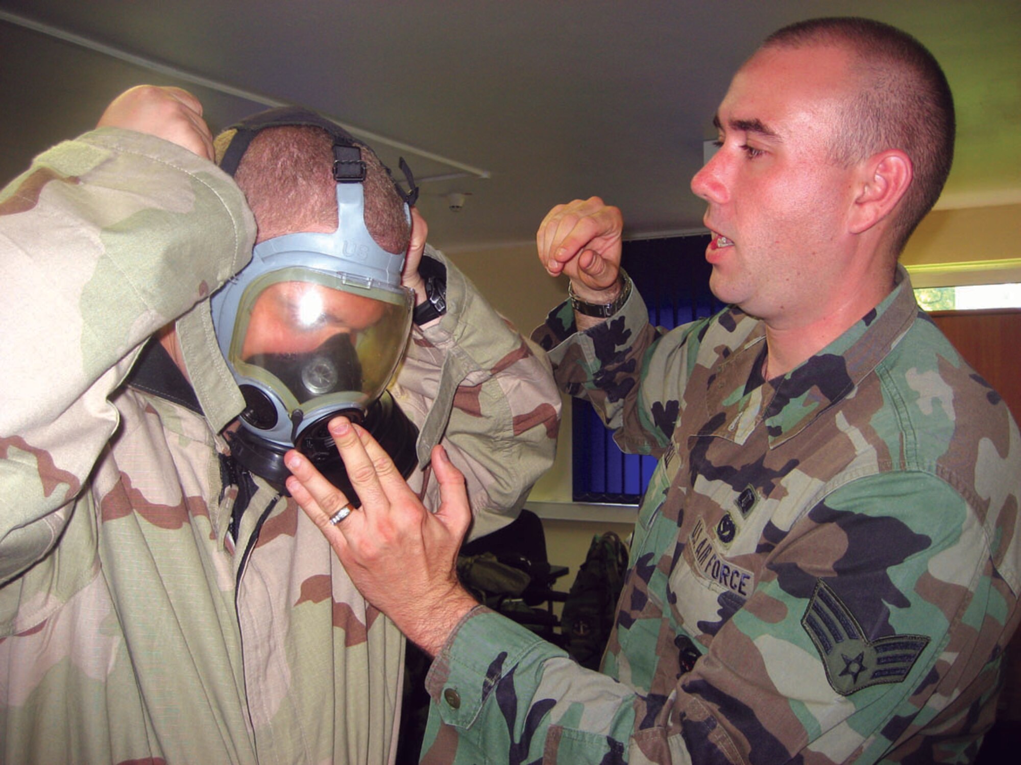 SPANGDAHLEM AIR BASE, GERMANY -- Airman 1st Class Daniel Farrell, 52nd Civil Engineer Squadron readiness and emergency management flight, assists Staff Sgt. Chris Parrish, 52nd Maintenance Operations Squadron, with a proper seal during Tuesday’s Chemical, Biological, Radiological, Nuclear and High-Yield Explosive defense training here. (US Air Force photo/by Staff Sgt. Andrea Knudson) 