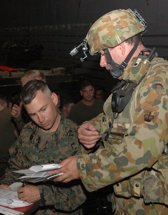 Royal Australian Army Warrant Officer Class 2  Robert J. Chandler and 31st Marine Expeditionary Unit Master Sgt. David R. Trump discuss amphibious armored vehicle launch plans at the landing dock on USS Juneau, June 20, 2007. Juneau is participating in Exercise Talisman Saber 07.