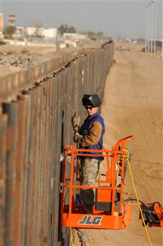 U.S. Army Spc. Michael J. Westall uses a motorized boom lift to get into position to weld the reinforcement of the primary steel border fence along the United States-Mexico border on June 7, 2007.  Westall is attached to the 188th Engineer Company, North Dakota Army National Guard and assigned to Task Force Diamondback. Task Force Diamondback's mission is to erect and reinforce segments of border fence and the construction of obstacles to help secure the Southwest United States-Mexico border. 