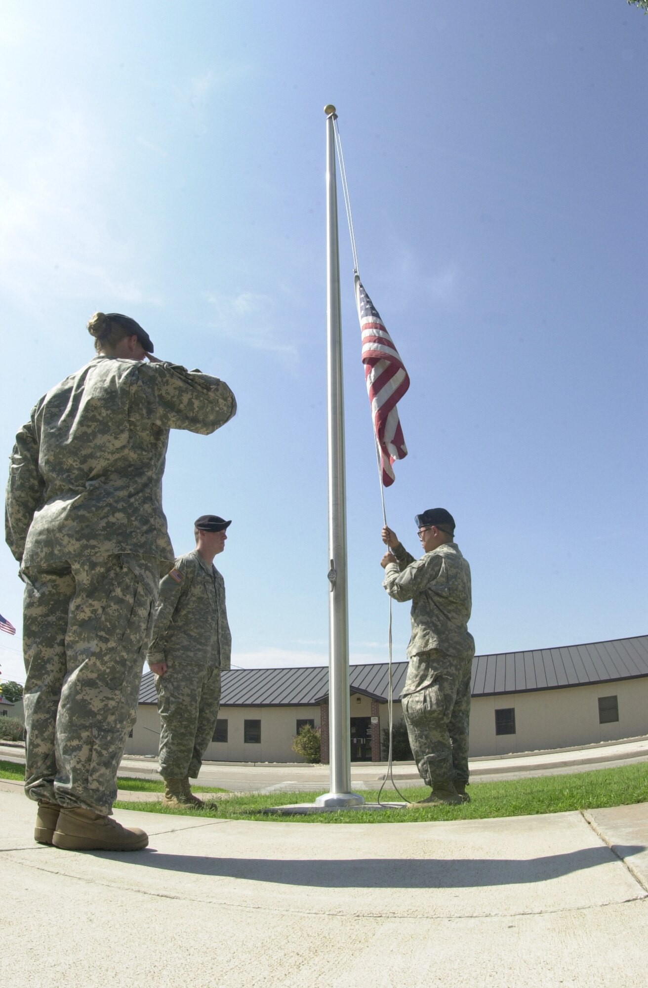 (From left to right) Sgt. 1st Class Susanne Watts salutes while Pfc. Kevin Bell and Spc. Hung Zhang ceremoniously lower the American flag which flies in front of the Vance Nolan Building, headquarters to the 344th Military Intelligence Battalion. The 344th retires the colors everyday during retreat, including weekends. The retreat ceremony serves a twofold purpose. It signals the end of the official duty day and serves as a ceremony for paying respect to the flag. 

When persons not assigned to a formation are outdoors and in uniform, on the first note of retreat, they should face the flag (if visible) or music and assume the position of parade rest.  At the beginning of the national anthem, individuals should stand at attention, salute and maintain the salute for the duration of the playing of the national anthem.