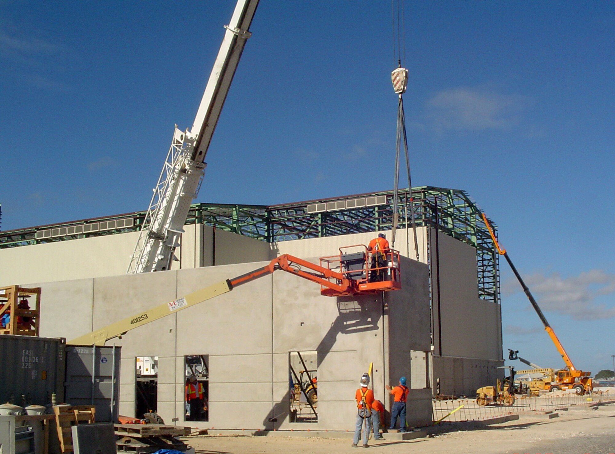 URS employees, contracted by the Air Force Center for Engineering and the Environment, use cranes and other heavy equipment to maneuver pre-case concrete walls into place for the new C-17 Globemaster III Corrosion Control Hangar at Hickam Air Force Base, Hawaii. The hangar will be used for painting and general maintenance functions for the eight C-17 aircraft assigned to Hickam AFB. (U.S. Air Force photo/Capt. Kevin Syzmanski)
