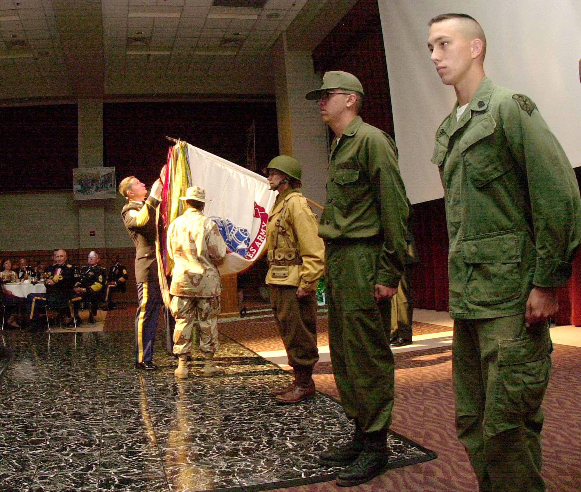 Command Sgt. Maj. Manuel Sanchez places streamers from the Army’s Operation Desert Storm and Desert Shield campaign on the Army service flag during a special streamer ceremony at the Army Ball Saturday. Student Soldiers wearing uniforms of the Army’s historic conflicts, such as the Vietnam and Korean Wars, stand at attention. (U.S. Air Force photo by Airman 1st Class Luis Loza Gutierrez)