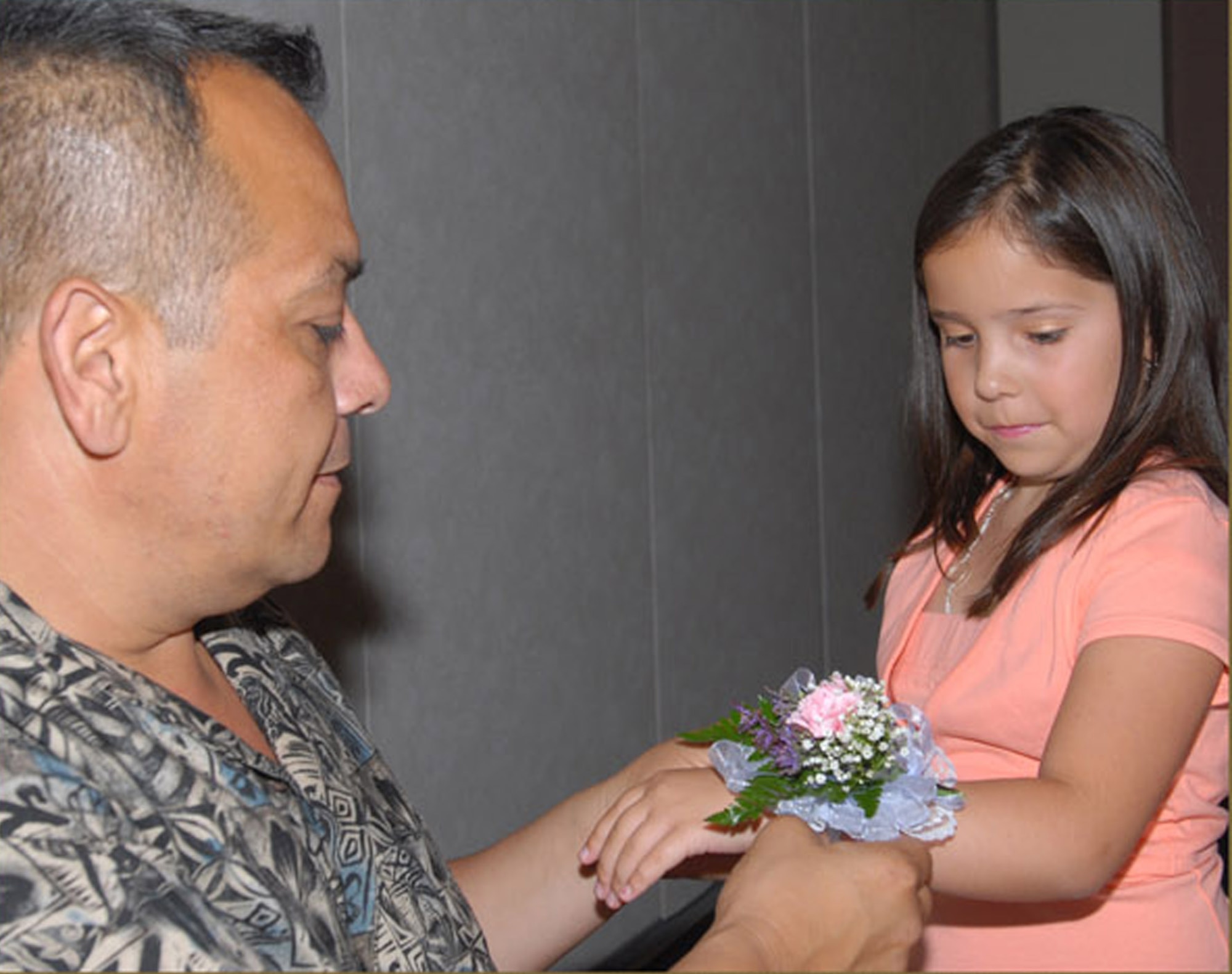 Deja Martinez watches as her dad, Senior Master Sgt. Robert Martinez, puts a corsage on her wrist. (U.S. Air Force photo by Staff Sgt. Angela Malek)
