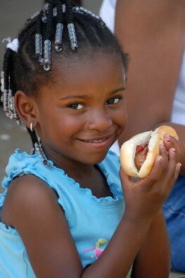Alexandra Foster, 4, a member of the Scott community, takes time from the many activities to enjoy a hot dog during Friday's Match Up Family Picnic.
