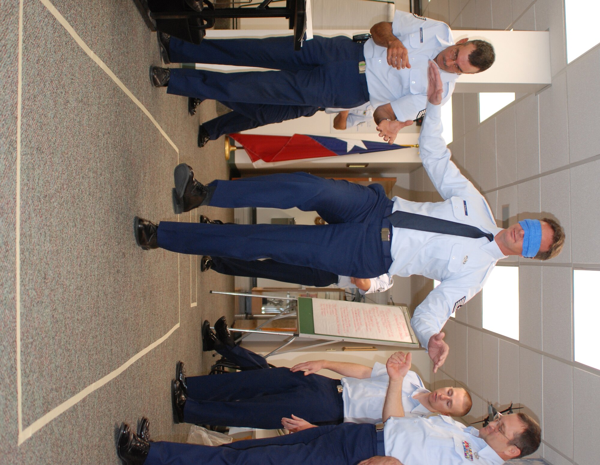 Tech. Sgt. Robert Staley (center) listens for his next movement instructions from Staff Sgt. Ryan Marley (second from right). Both 301st Fighter Wing Air Force Reservists are working together to keep from "being blown up" by simulated landmines. Tech. Sgt. Larry Driskill (far left) and Tech. Sgt. Chris Yancey (far right) assist in Sergeant Staley's balancing act. Only at the end did Sergeant Staley realize he was navagating an empty mine field. The Noncommissioned Officer Leadership Development Course exercise, held at Naval Air Station Joint Reserve Base Fort Worth, Texas, was used to help students learn to listen and follow explicit instructions without the ability to give verbal feedback. (U.S. Air Force Photo/Tech. Sgt. Julie Briden-Garcia)