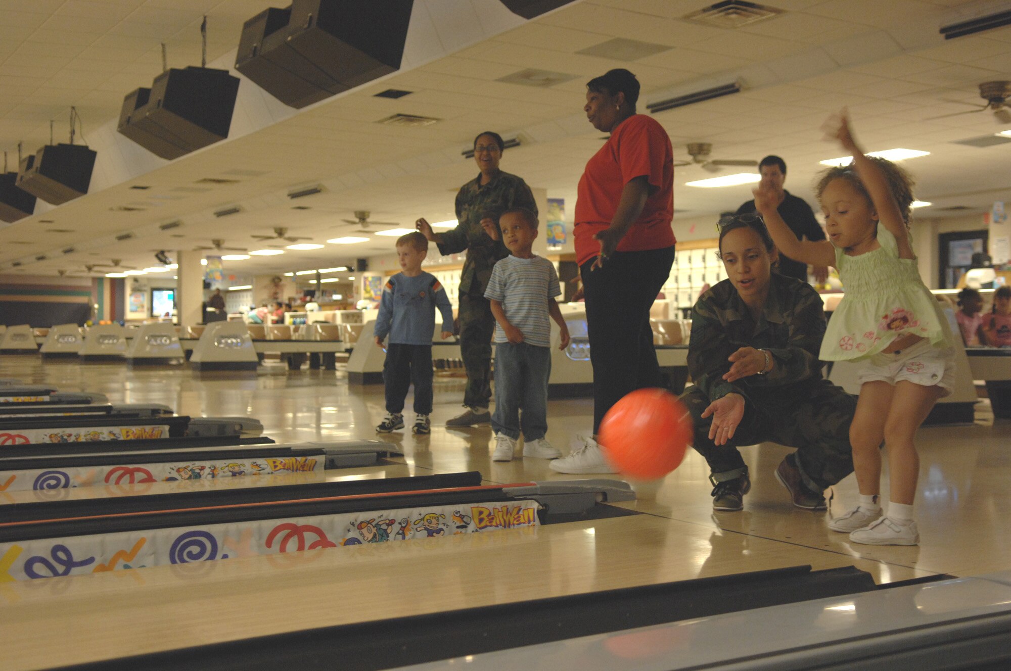 Jeniya Taylor tosses the bowling ball down the lane with guidance from her mother, Staff Sgt. Jenny Taylor, 30th Intelligence Squadron, as parents, children and teachers take time out for bowling here June 14.  Throughout the summer, children at the Russ Child Development Center take a number of field trips around Langley including walks to the bowling center, library, pool and Eagle Park. (U.S. Air Force Photo/Senior Airman Tabitha Kuykendall)