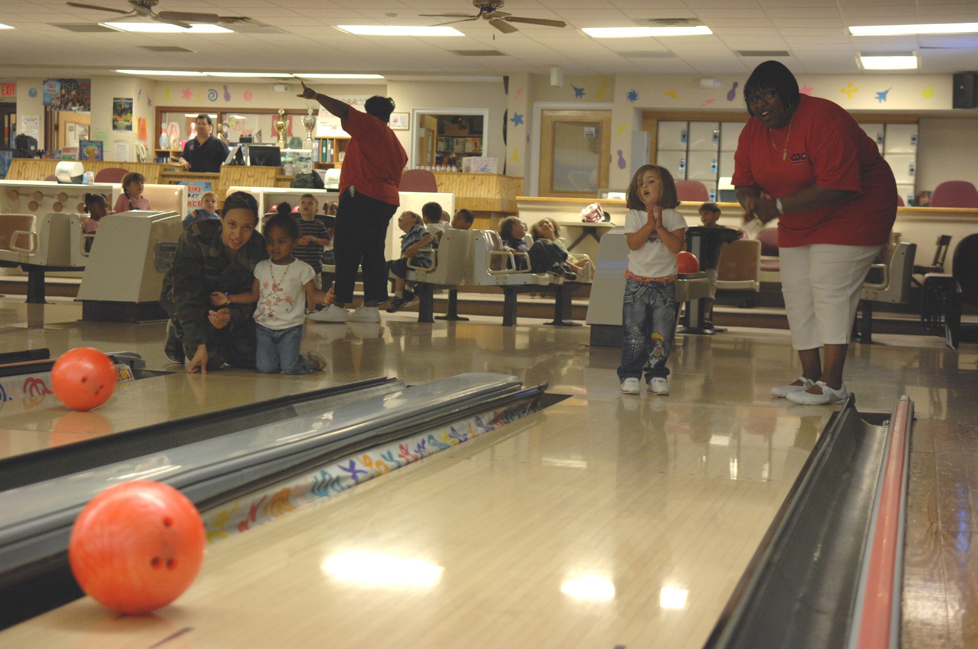 From left: Staff Sgt. Jenny Taylor, 30th Intelligence Squadron, and Aniya Doctor, daughter of Staff Sgt. Shirelle Eichelberger, Air Combat Command promotions,  watch Aniya’s bowling ball make its way down the lane as Savannah Simon, daughter of Senior Airman Stephanie Simon, 1st Aerospace Medicine Squadron public health technician, and Gloria Pat Brown, childcare provider, cheer for Savannah's ball here June 14. Throughout the summer, children at the Russ Child Development Center take a number of field trips around Langley including walks to the bowling center, library, pool and Eagle Park. (U.S. Air Force Photo/Senior Airman Tabitha Kuykendall)