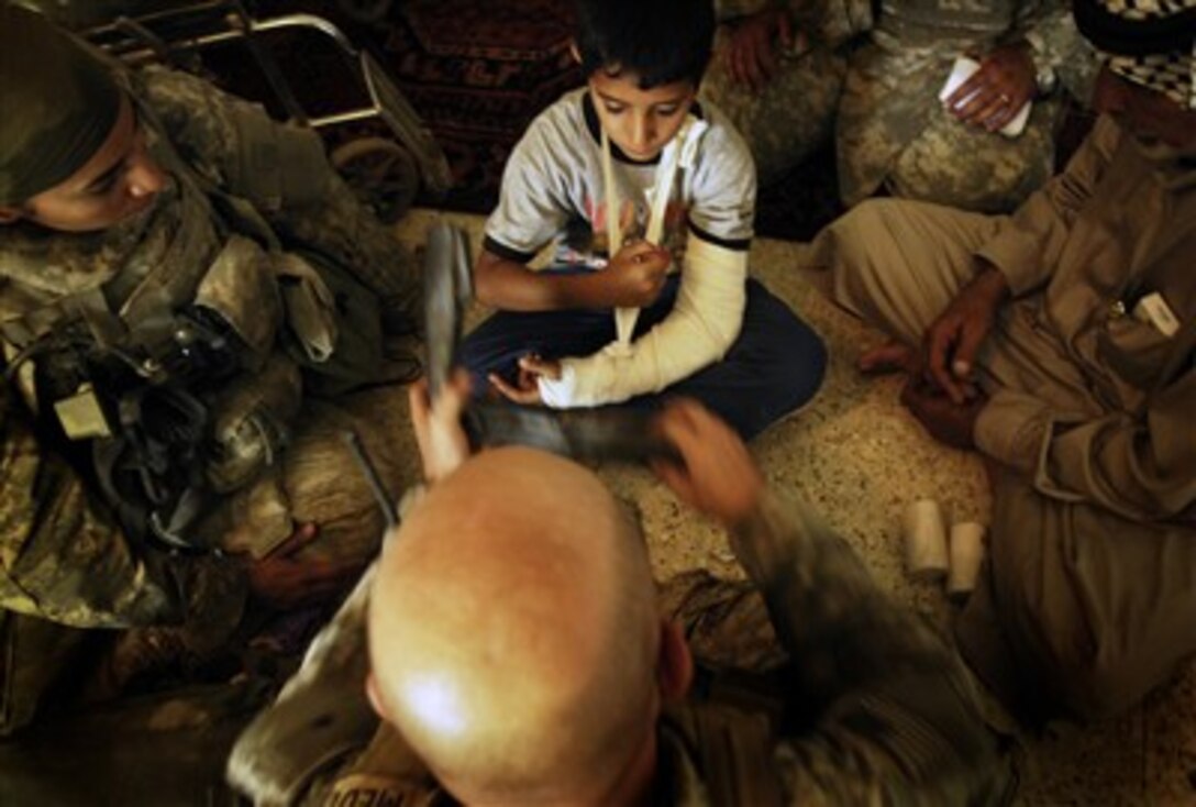 U.S. Army soldiers bandage and splint a boy's arm.