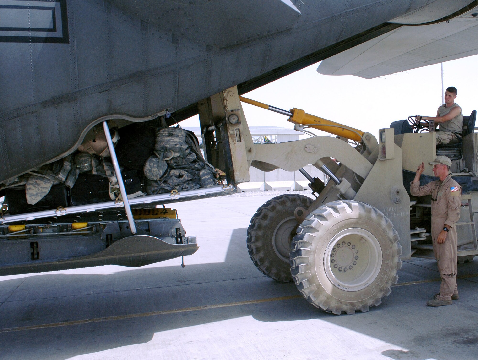 Senior Airman Patrick Keefe (far right), 774th Expeditionary Airlift Squadron loadmaster, directs a forklift carrying passenger luggage into the cargo area of a C-130 at Kandahar Airfield, Afghanistan. Airman Keefe is deployed from Wyoming's Air National Guard, Cheyenne, Wyo. (photo by Staff Sgt. Craig Seals)