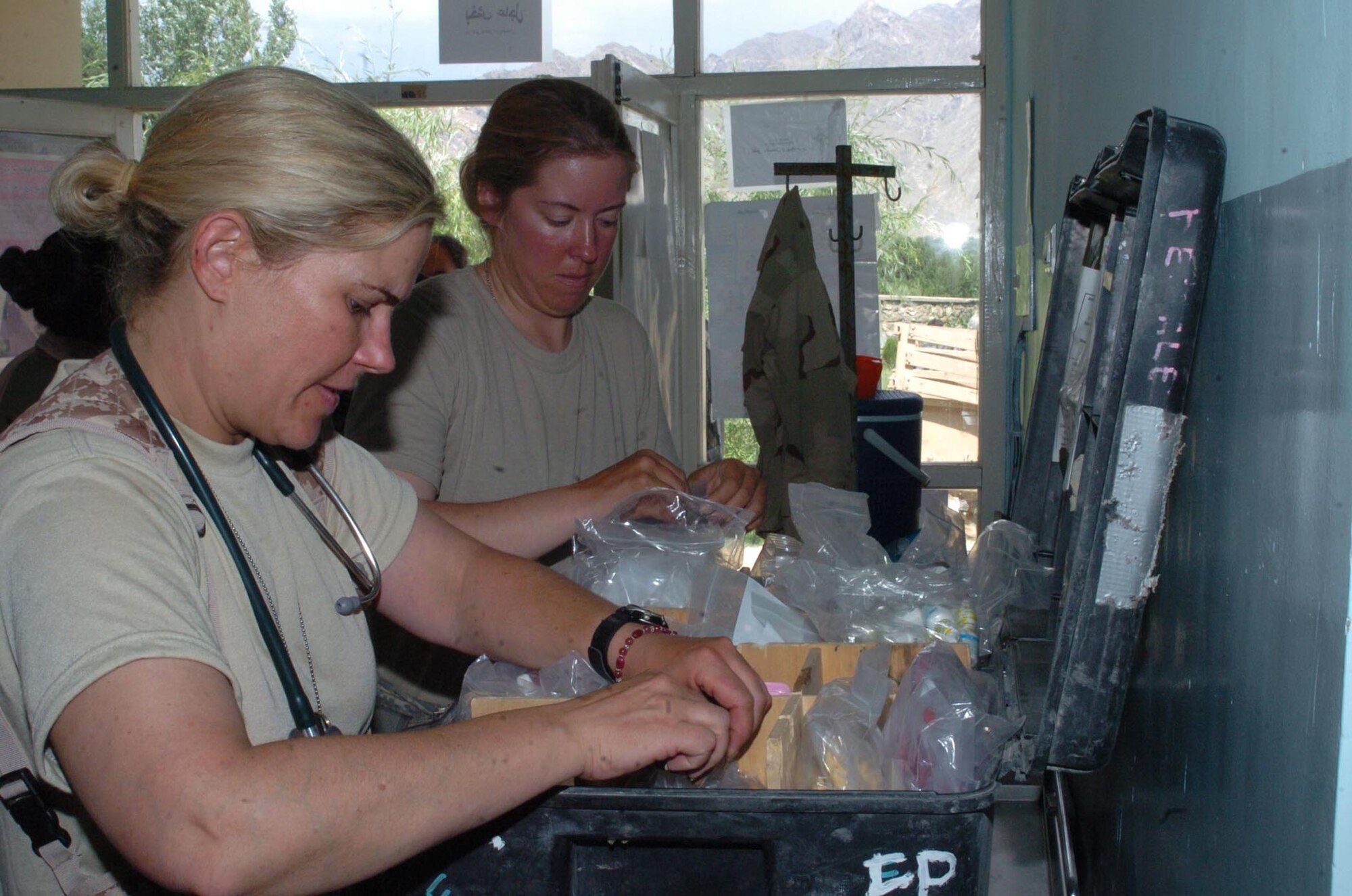 (Left to right) Navy Lt. Jennifer Rosen, doctor of general medicine, and Tech. Sgt. Deborah Taylor, Bagram Provincial Reconstruction team medic, organize medications for distribution prior to a a medical engagement in Nijrab district June 22. Nijrab doctors and members of the Bagram Provincial work side-by-side to provide care to more than 160 local Afghans. (U.S. Air Force photo by Senior Airman Dilia DeGrego)
