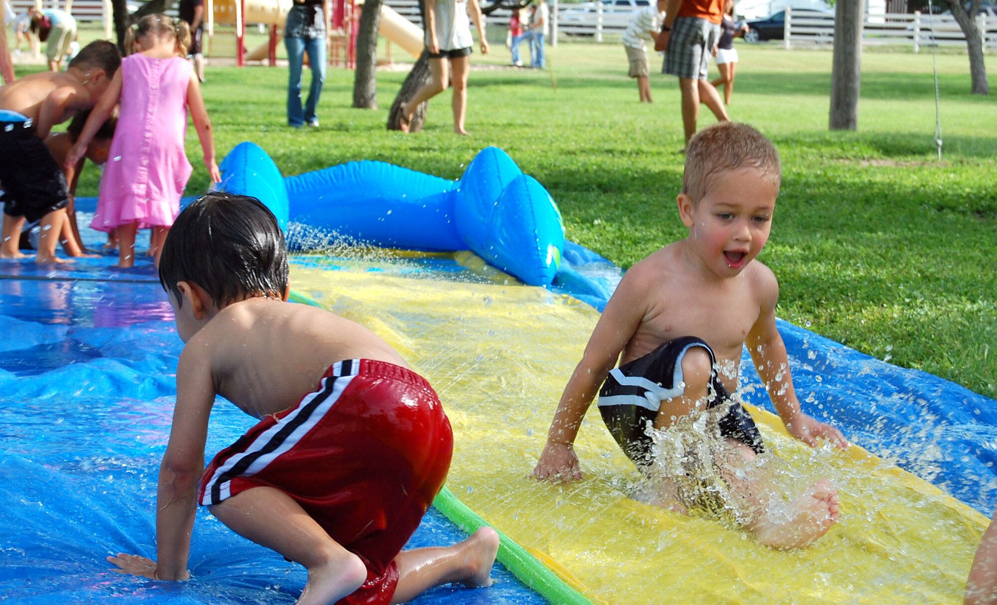 LAUGHLIN AIR FORCE BASE, Texas -- Justin Kazmirski, 3, Son of Staff Sgt. Sanita Kazmirski, 85th Flying Training Squadron and Master Sgt. Stephen Kazmirski, 47th Mission Support Group First Sergeant, skims down the Slip-n-Slide to cool off with several other children, at Laughlin's Second Annual Wild West Day. (U.S. Air Force photo by Airman Sara Csurilla) 