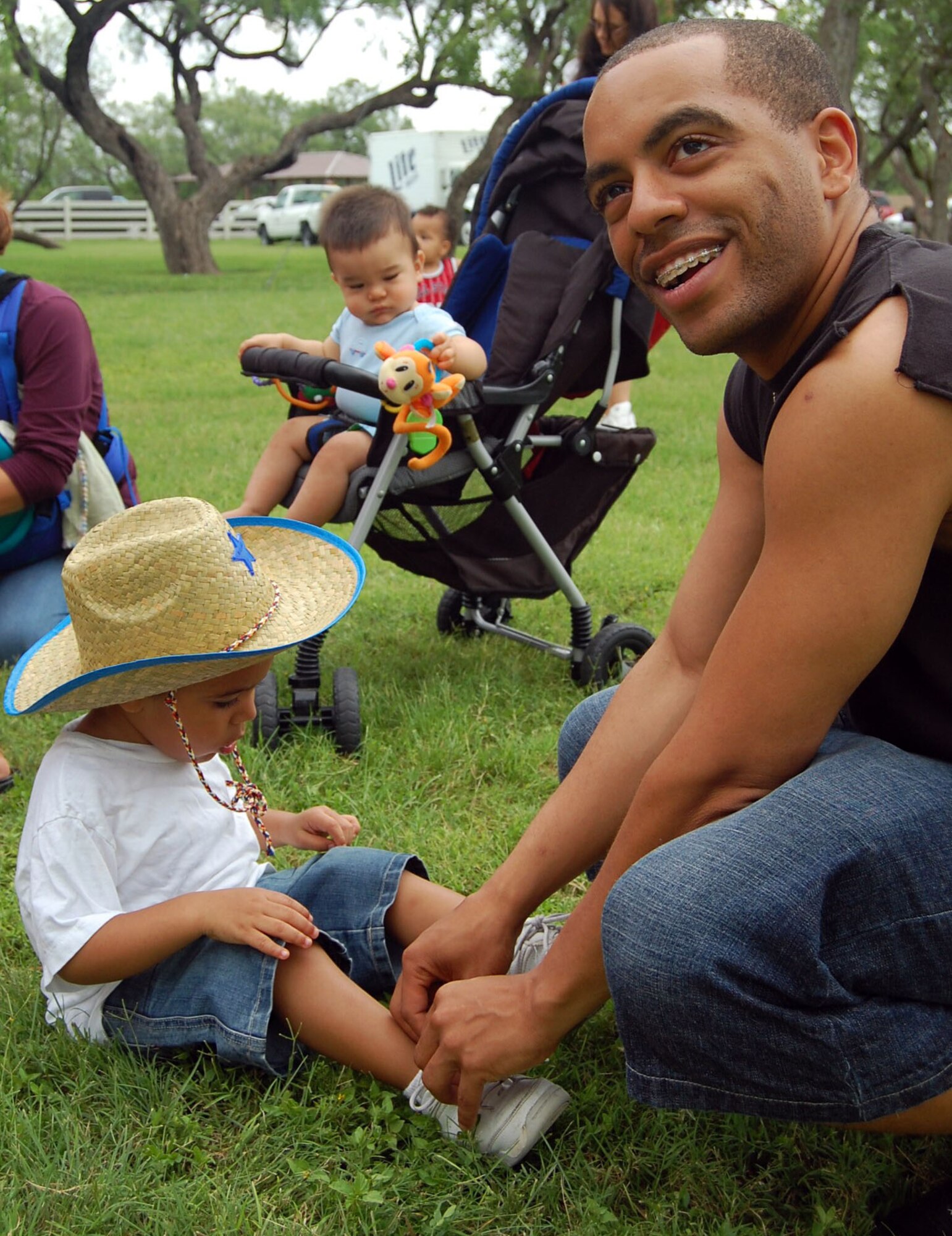 LAUGHLIN AIR FORCE BASE, Texas -- Dion Henderson, 2, son of Carolina Henderson and Staff Sgt. Roderick Henderson, 47th Security Forces Squadron, gets help from his father taking his shoes off so he can play in the bounce castle at Laughlin's Second Annual Wild West Day June 22. There were numerous activities for kids of all ages to participate in, such as pony rides, 'Dunk the Dork', a Slip-n-Slide and many more. (U.S. Air Force photo by Airman Sara Csurilla) 

