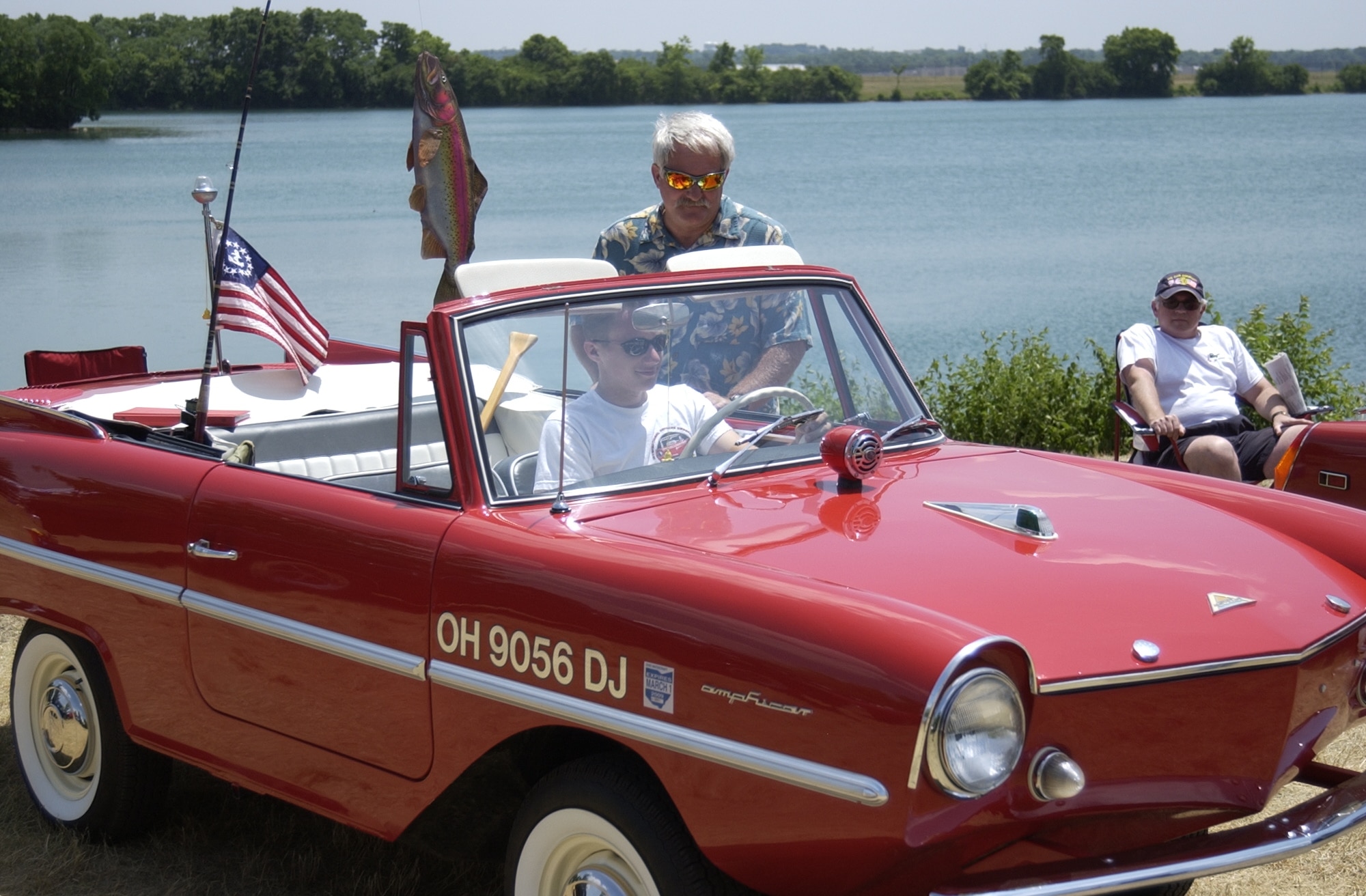 Colin Bayman sits behind the wheel of a restored Amphicar as his dad, Mike Bayman, points out some features of his self-restored 1960s West German vehicle that is part car, part boat at Bass Lake on Wright-Patterson Air Force Base, Ohio. Mike Bayman is an alarm technician with the 88th Air Base Wing Civil Engineer directorate. (U.S. Air Force photo/Staff Sgt. Andrew Hafey)