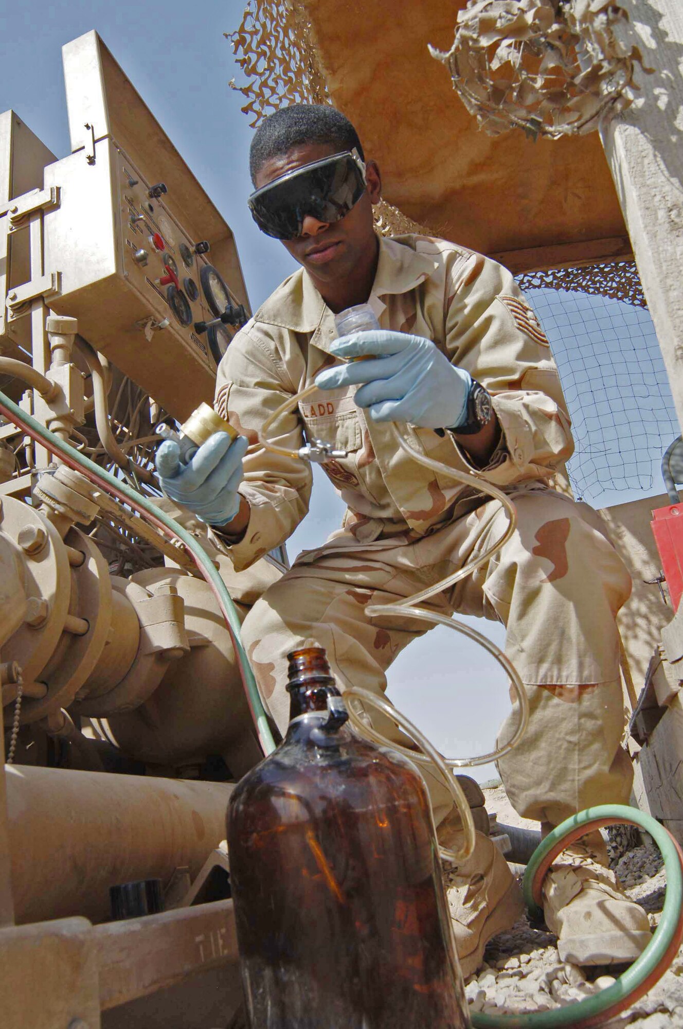 Tech. Sgt. Terrance Ladd attaches a filter to a fuel line to test JP-8 for water and contamination June 17 at Sather Air Base, Iraq. The fuel is pushed through a fabric disc from the base's fuel source and the disc will reveal its condition. The brown bottle collects the filtered fuel and is dumped back into the tank. Sergeant Ladd is a fuels lab technician assigned to the 447th Expeditionary Logistics Readiness Squadron. (U.S. Air Force photo/Tech. Sgt. Russell Wicke)