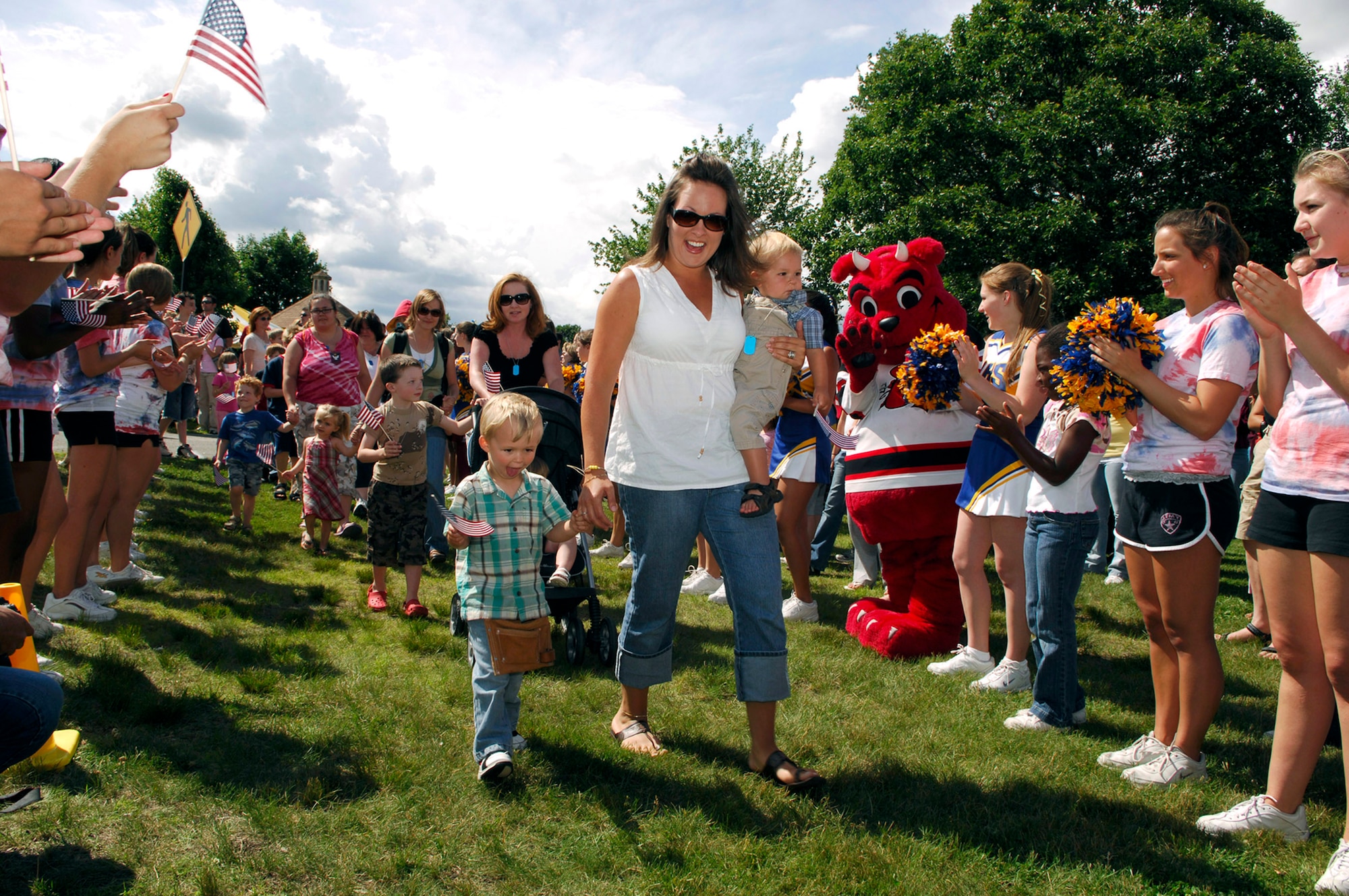 Families of Airmen who recently deployed marched into a cheering crowd waving American flags during Heroes' Homecoming June 22 at Hanscom Air Force Base, Mass. During the celebration, the community formally welcomed home more than 60 servicemembers who had deployed within the last six months. Hundreds of base members, family and friends gathered during the ceremony. (U.S. Air Force photo/Mark Wyatt)