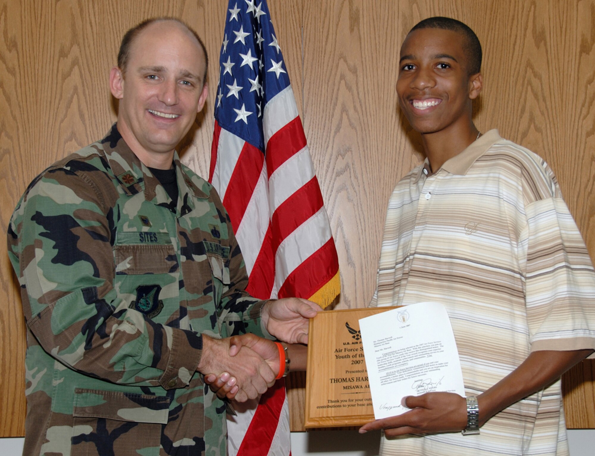MISAWA AIR BASE, Japan -- Thomas Harwell is presented a plaque June 25 here by Maj. Timothy Sites, 35th Services Squadron commander, for being selected as the 2007 Air Force Services Youth of the Year for Misawa. The high-school graduate also received $1,000 for college. He earned the award for his base and community contributions. Thomas is the son of Master Sgt. Barry and Netra Harwell, 35th Security Forces Squadron. (U.S. Air Force photo by Senior Airman Laura McFarlane)