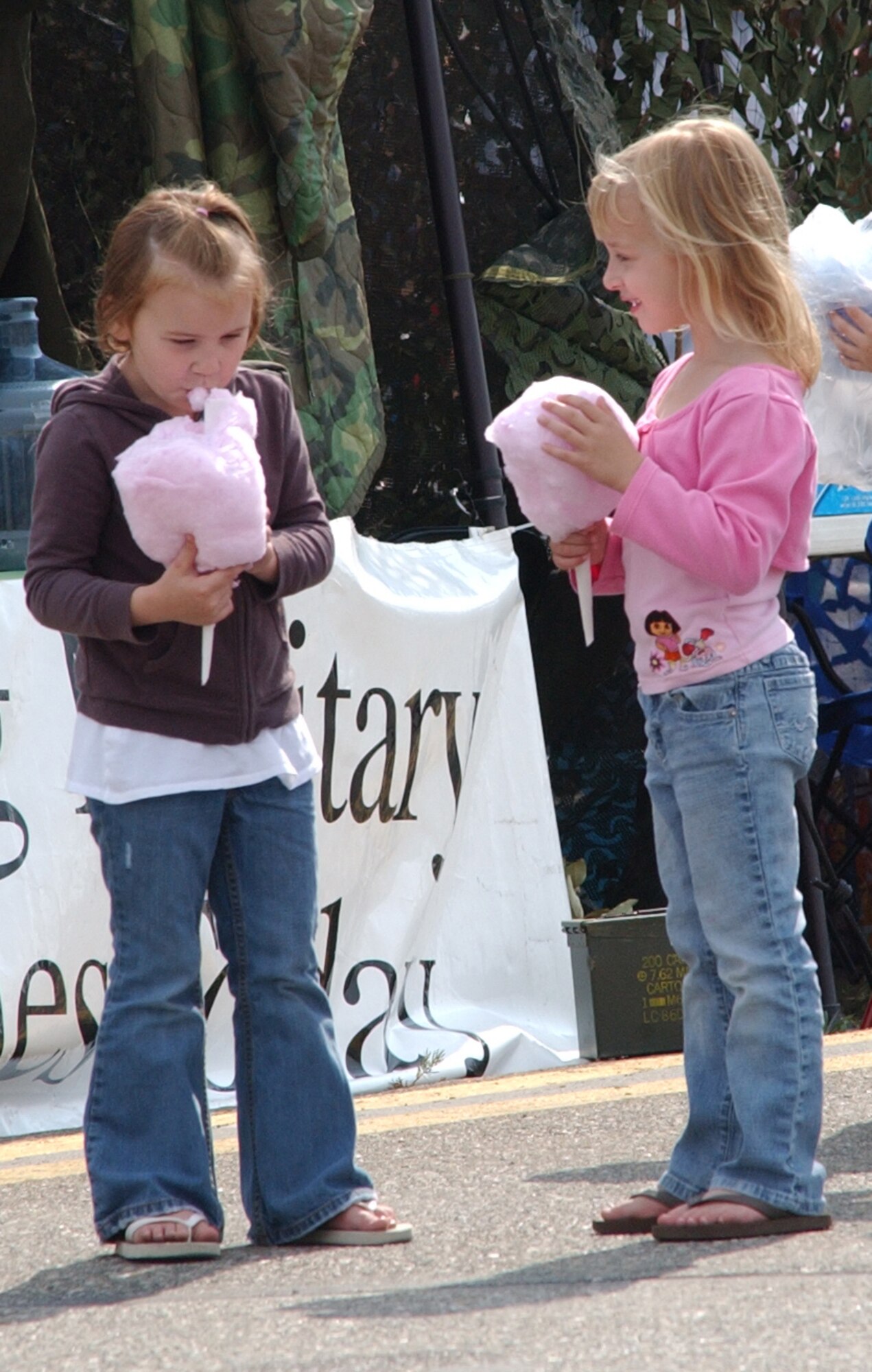 EIELSON AIR FORCE BASE, Alaska--Hayley Brooks and Abbey Miller take a break to enjoy some cotton candy during  the 2007 Soaring into Solstice Open House June 23 here. More than 25,000 people attended the all-day event featuring aerial and ground demonstrations including flybys, simulated airfield attacks, and aerobatic maneuvers as well as concessions, live music and many aircraft displays. (U.S. Air Force photo by Senior Airman Justin Weaver)