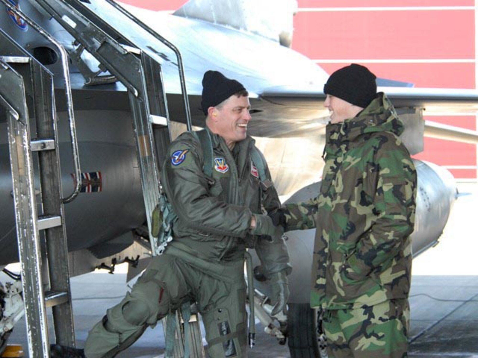 Col. Cecil J. "Bud" Hensel, North Dakota Air National Guard pilot, shakes hands with his son Senior Airman Bryan M. Hensel, 119th Maintenance Squadron crew chief, after successful completion of Col. hensels's last flight in an F-16.