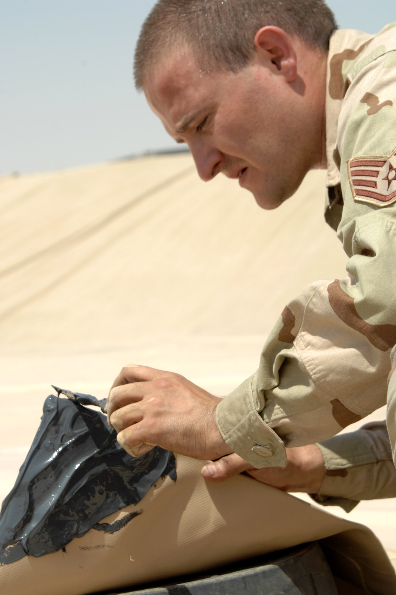 Staff Sgt. Mark Chance seals a corner of a new fuel bladder during installation June 19 at Kirkuk Regional Air Base, Iraq.  The bladder will be filled with JP-8 jet fuel.  Fuel storage bladders are collapsible, flexible storage containers that provide temporary as well as long term fuel storage.  Sergeant Chance is with the 506th Expeditionary Logistics Readiness Squadron.  (U.S. Air Force photo/Senior Airman Kristin Ruleau)

