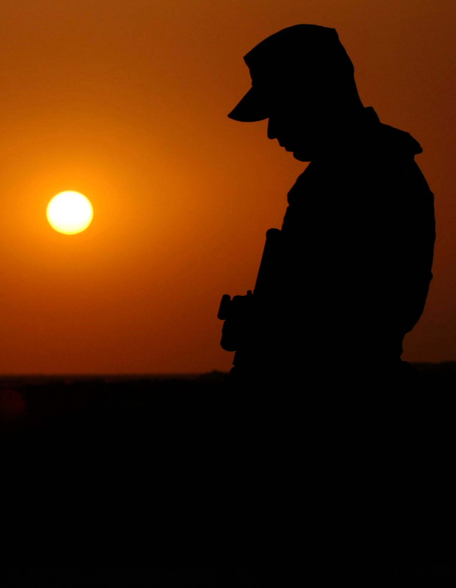 Senior Airman Dwayne Solis stands watch over the Ali Air Base, Iraq, flightline as the sun begins to set June 22. Airman Solis, a member of the 407th Expeditionary Security Forces Squadron, is assigned to flightline defense, protecting U.S. and coalition assets from insurgent intelligence gathering efforts and attacks. (U.S. Air Force photo/Master Sgt. Robert W. Valenca)