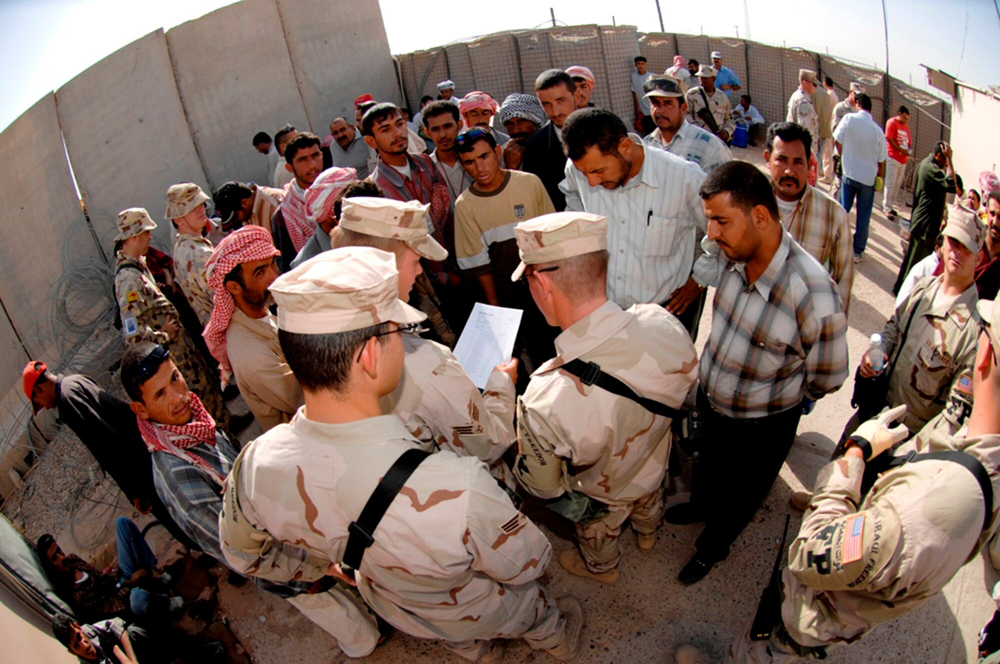 Members of the 407th Expeditionary Security Forces Squadron's Force Protection Flight at Ali Air Base, Iraq, review a list and hand out badges to local nationals waiting to be escorted on base to work.  This process is done every day to ensure the safety and security of the bases personnel and assets. FPF Airmen monitor local and third country nationals to detect suspicious activity, augment security forces during increased force protection conditions, and monitor and maintain installation security measures. (U.S. Air Force photo/Master Sgt. Robert W. Valenca) 