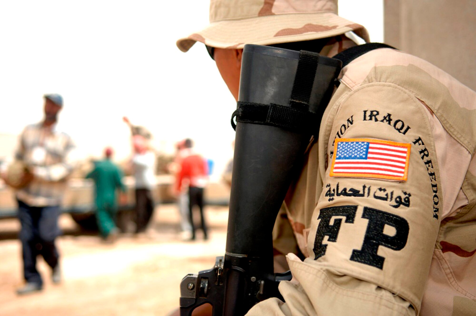 Airman 1st Class Christian Concepcion keeps a watchful eye on local nationals as they move sandbags on Ali Air Base, Iraq, to help fortify buildings in case of an attack. Airman Concepcion, a services specialist with the 99th Services Squadron at Nellis Air Force Base, Nev., is currently deployed working outside of his career field as a member of the 407th Expeditionary Security Forces Squadron's Force Protection Flight.  FPF Airmen monitor local and third country nationals to detect suspicious activity, augment security forces during increased force protection conditions, and monitor and maintain installation security measures. (U.S. Air Force photo/Master Sgt. Robert W. Valenca)