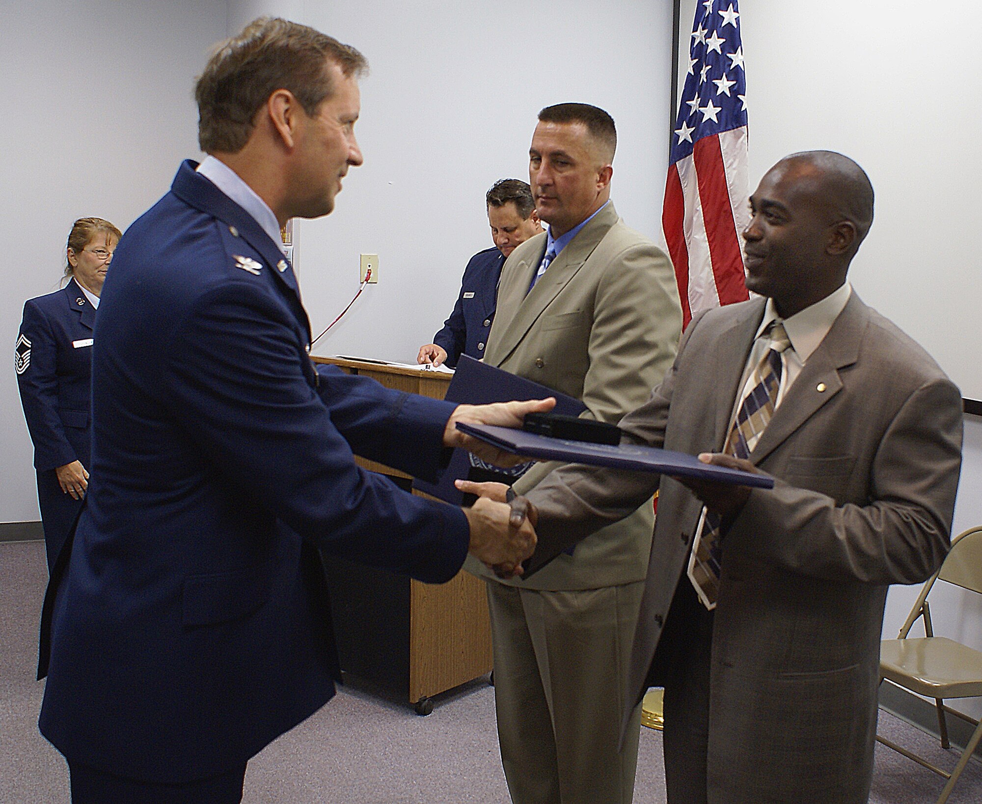 Col. Scott “Foot” Goodfellow, 482nd Operations Group Commander, thanks the husbands of Master Sgt. Tammy Mobley, Eugene (right), and Master Sgt. Danielle Lintz, Jody (center). Sergeants Mobley and Lintz retired in a dual ceremony on June 9 here. (U.S. Air Force photo/Dan Galindo)