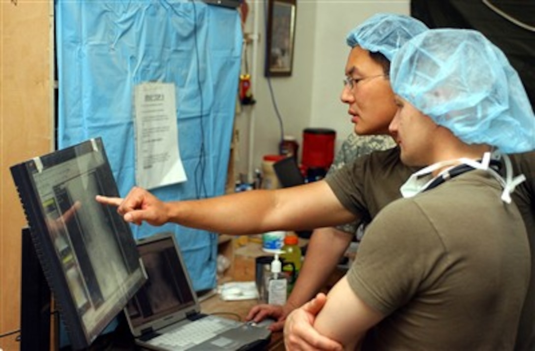 U.S. medical personnel with the Charlie Medical team discuss an x-ray of an Iraqi police officer at Camp Ramadi, Iraq, on June 20, 2007.  The team is providing treatment to Iraqi police officers after a vehicle borne improvised explosive device detonated in Ramadi. 