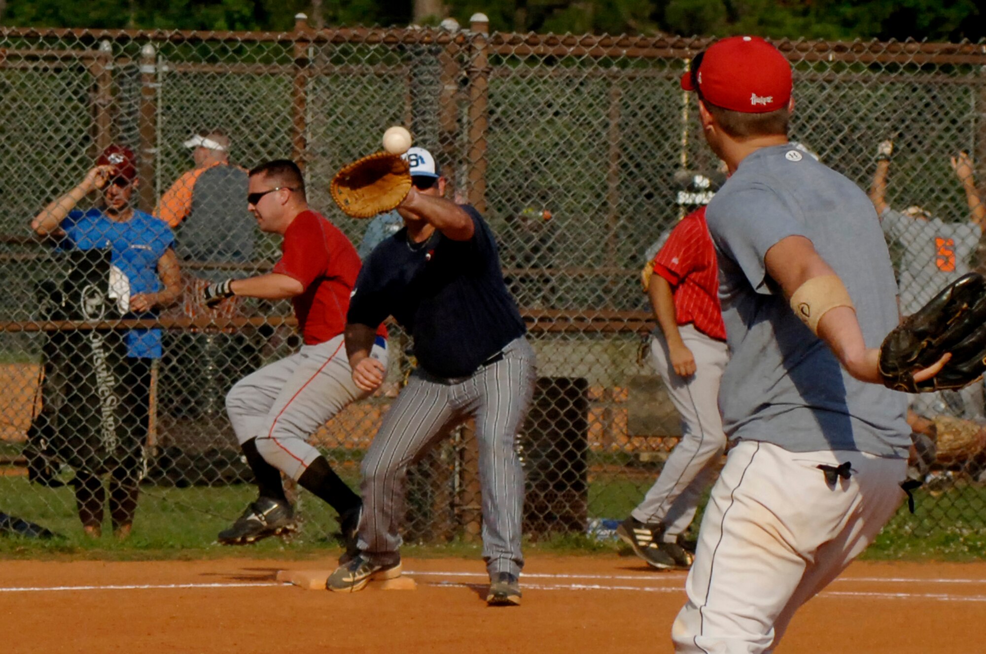 Harry Carnell, 437th Aerial Port Squadron, runs through first base safely as Matt Cunningham, 437th Operations Support Squadron, throws the ball to his teammate, Robert Sadwick during the game on base Tuesday. (U.S. Air Force photo/Airman 1st Class Nicholas Pilch) 
