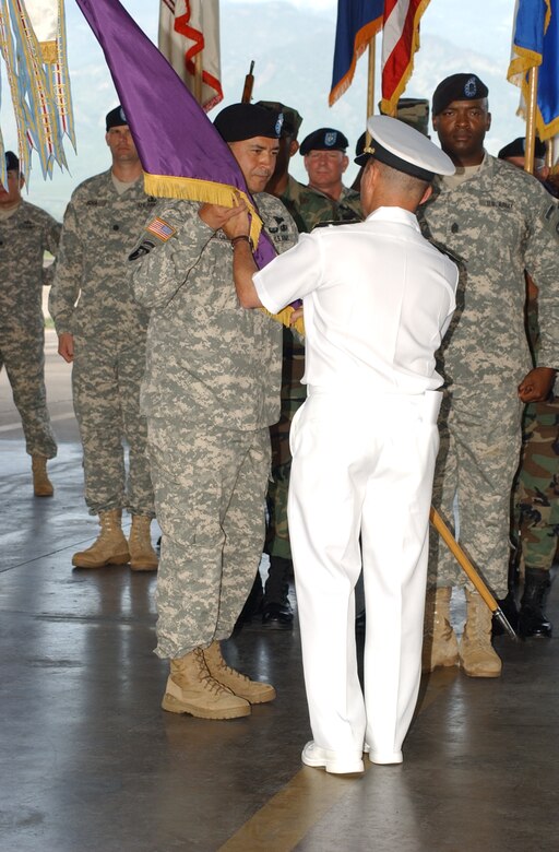 Army Col. Marcus DeOliveira assumes command of Joint Task Force-Bravo by accepting the JTF-Bravo colors from Navy Adm. James Stavridis, United States Southern Command commander, during the JTF-Bravo change of command ceremony June 27 at the Soto Cano Air Base Fire Department. Colonel DeOlivera took over command from Col. Christopher Hughes, who served as commander for the past year. Colonel DeOlivera arrived from Fort Polk, La., where he was senior officer in charge for Task Force 3 at the Joint Readiness Training Center. U.S. Air Force photo by Martin Chahin.