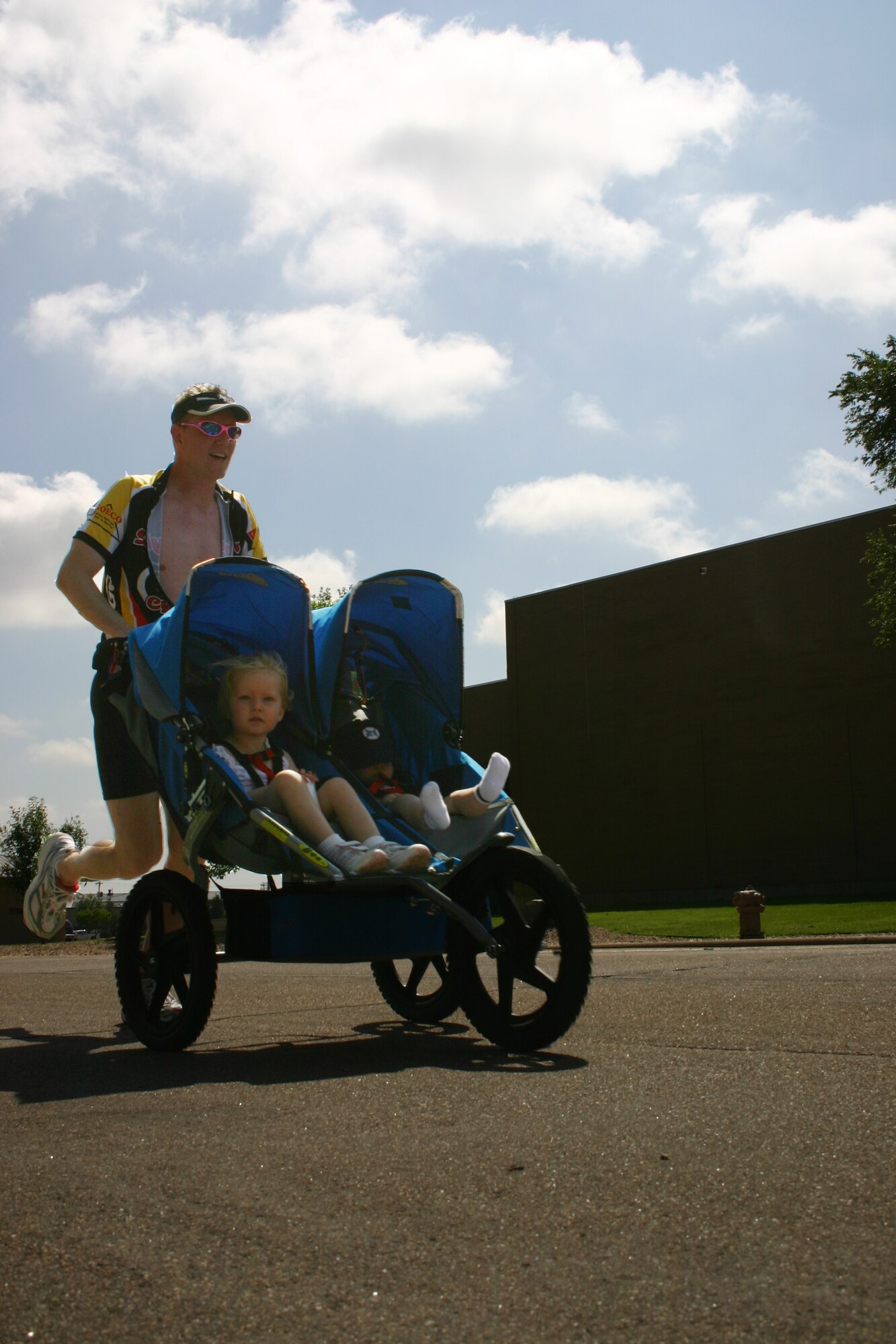 Maj. Matt Davis, 27th Equipment Maintenance Squadron, completes the home stretch of the five kilometer run with daughter Ella and son Bennett with him the whole time. Participants swam 500 meters, biked 10 kilometers, and ran five kilometers during the triathlon held by the 27th Services Squadron. (U.S. Air Force photo by Airman Elliott Sprehe)