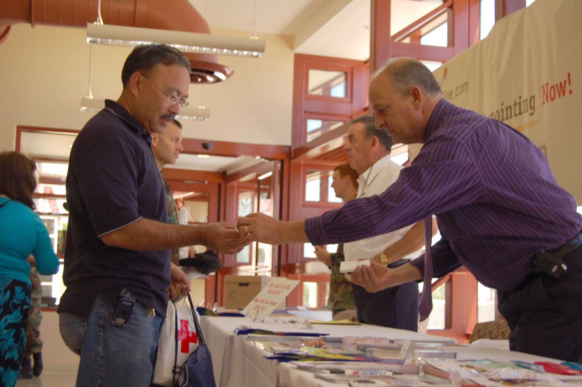 John Thompson (right), hearing aid consultant, shows his product's information to Chris Borja (left), 95th Medical Support Squadron site manager, during the Men's Health Fair at the medical clinic lobby Tuesday. The fair was hosted by the 95th Medical Group. (Photo by Airman 1st Class Julius Delos Reyes)