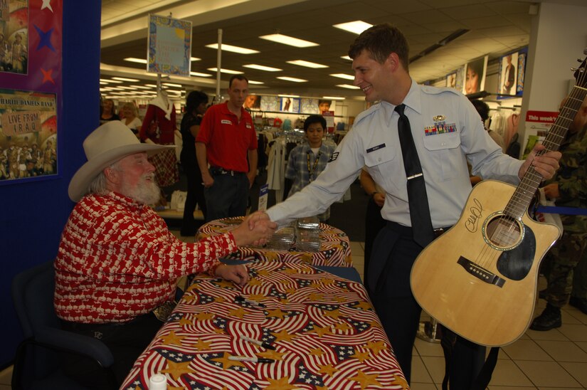 Country Western singing star Charlie Daniels shakes the hand of Senior Airman Tyler Perry, 316th Contracting Sqadron contracting specialist after signing a guitar during an event hosted by AAFES at the Base Exchange Tuesday. (U.S. Air Force photo/Tech. Sgt. Christopher Matthews)