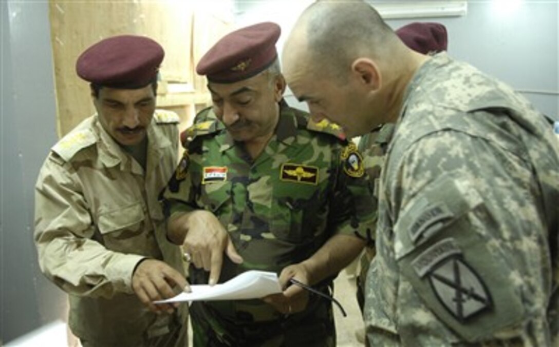 Capt. Brent Dittenber, commander, Alpha Company, 4th Battalion, 31st Infantry Regiment, 2nd Brigade Combat Team, 10th Mountain Division (Light Infantry), from Fort Drum, N.Y., checks the names of applicants for the Iraqi police force with Iraqi army staff officers. The recruitment drive was June 23-25 in Yusufiyah.