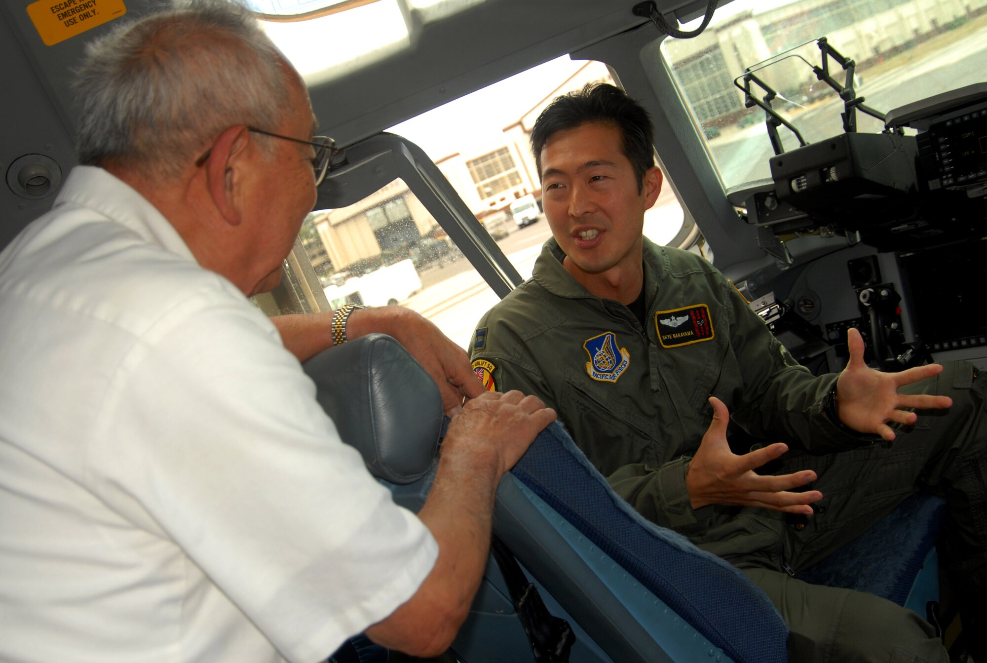 Captain Skye Nakayama talks about the capabilities of the C-17 Globemaster III with World War II veteran Sam Fujikawa during a visit June 25 to Hickam Air Force Base, Hawaii.  Mr. Fujikawa and other members of the 100th Infantry Battalion were touring the base.  Captain Nakayama a pilot with the Hawaii Air National Guard's 154th Wing.  (U.S. Air Force photo/Master Sgt. Kristen M. Higgins)