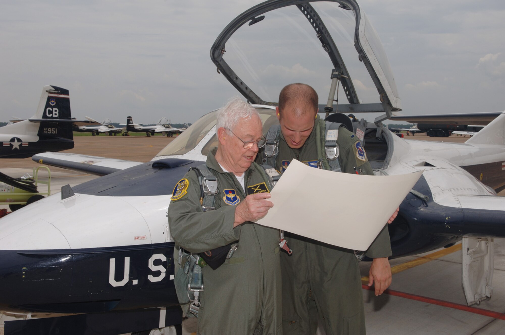 Mr. Keith Ferris, Air Force aviation artist, presents 1st Lt. Timothy Grebs, 37th Flying Training Squadron Instructor Pilot, with a lithograph of the old T-37 paint scheme. (U.S. Air Force Photo by Kenn Brown)
