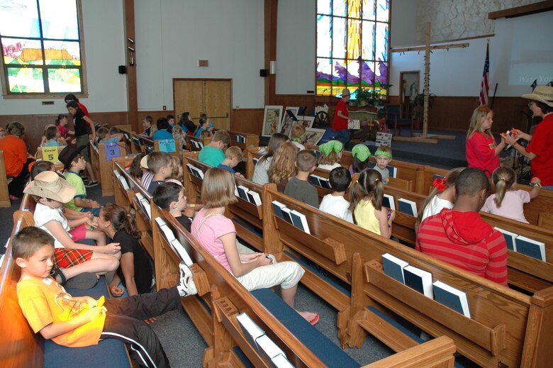 As the day comes to an end, Little Warriors gather in the pews for sing-alongs, prayer and the cross lighting activity. (U.S. Air Force photo / Airman 1st Class Dillon White)