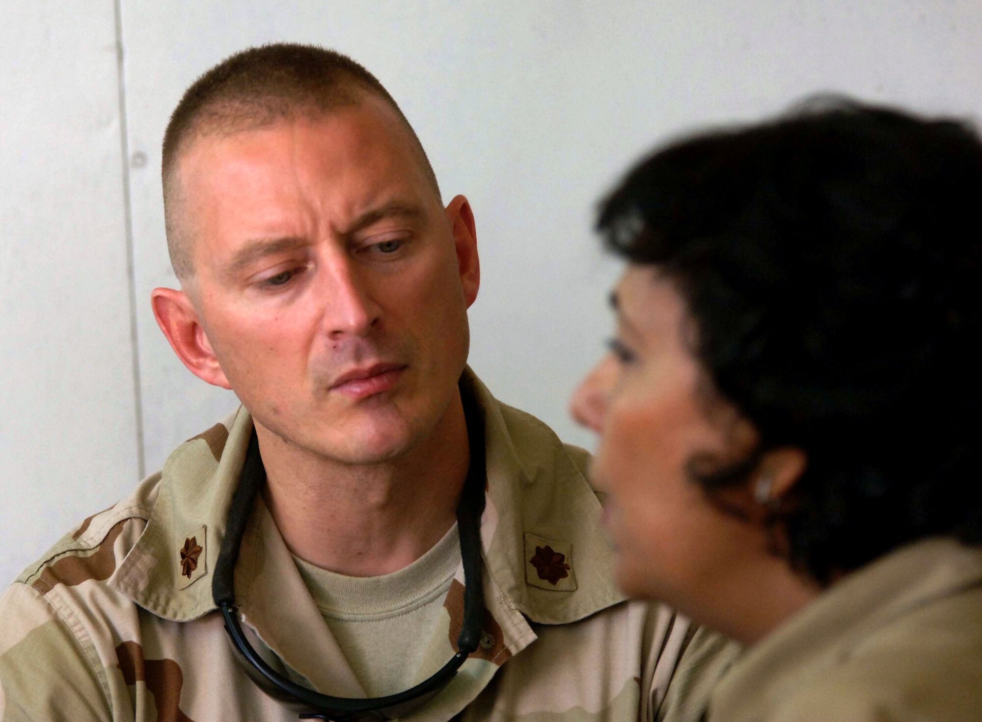 Maj. (Dr.) Andrew Chontos (left) listens to an Iraqi mother speak to a translator about an ailment June 21 at the Civil-Military Operations Center medical clinic at Camp Striker, Iraq. Major Chontos is a 447th Expeditionary Medical Squadron medical doctor. The Civil-Military Operations Center medical clinic provides free medical service to impoverished Iraqi citizens. (U.S. Air Force photo/Tech. Sgt. Russell Wicke)