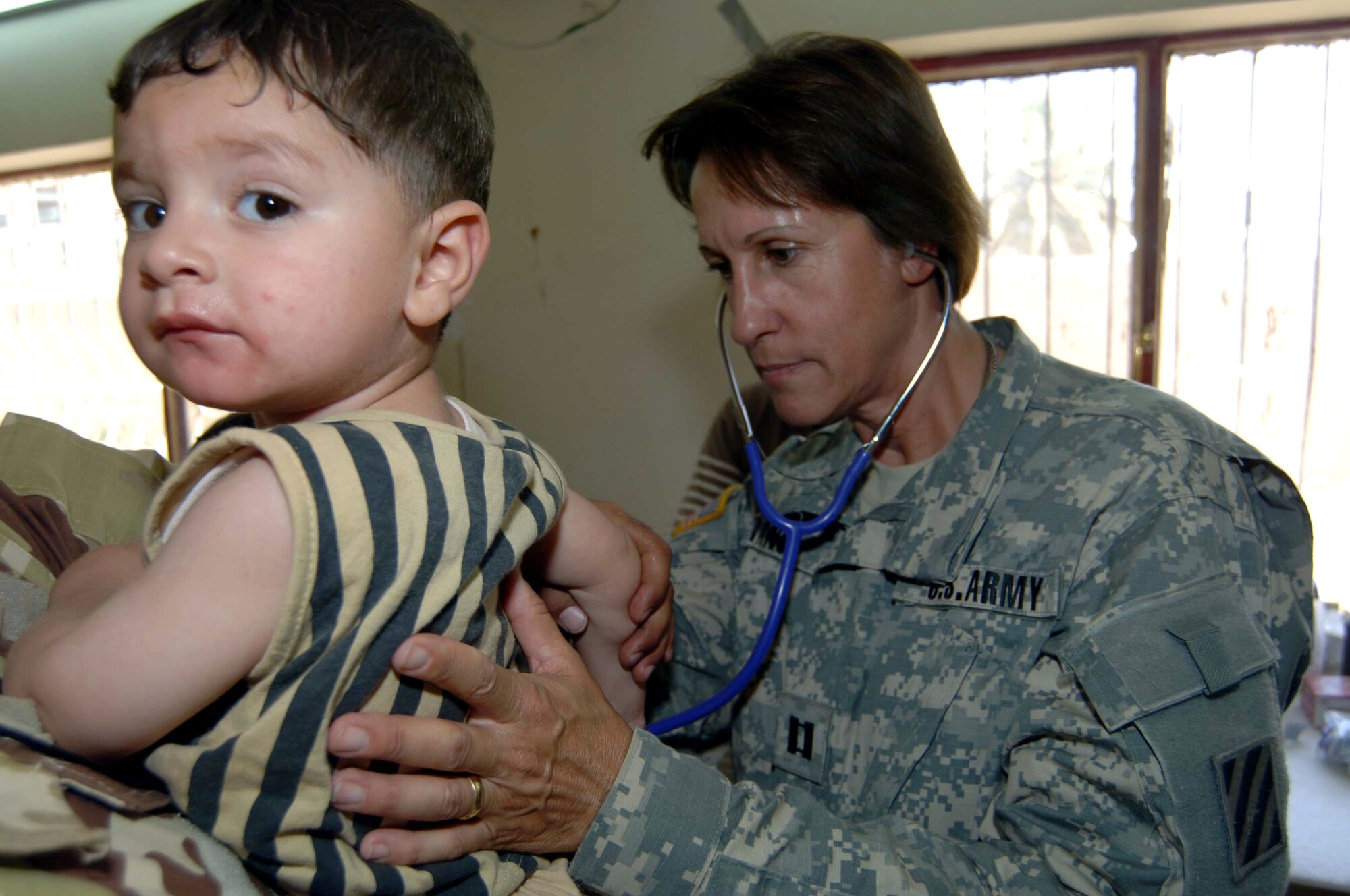 Army Capt. Gail Evans provides care to an Iraqi child June 21 at the Civil-Military Operations Center medical clinic at Camp Striker, Iraq. Captain Evans is a 478th Civil Affairs Battalion medic. The Civil-Military Operations Center medical clinic provides free medical service to impoverished Iraqi citizens. (U.S. Air Force photo/Tech. Sgt. Russell Wicke)

