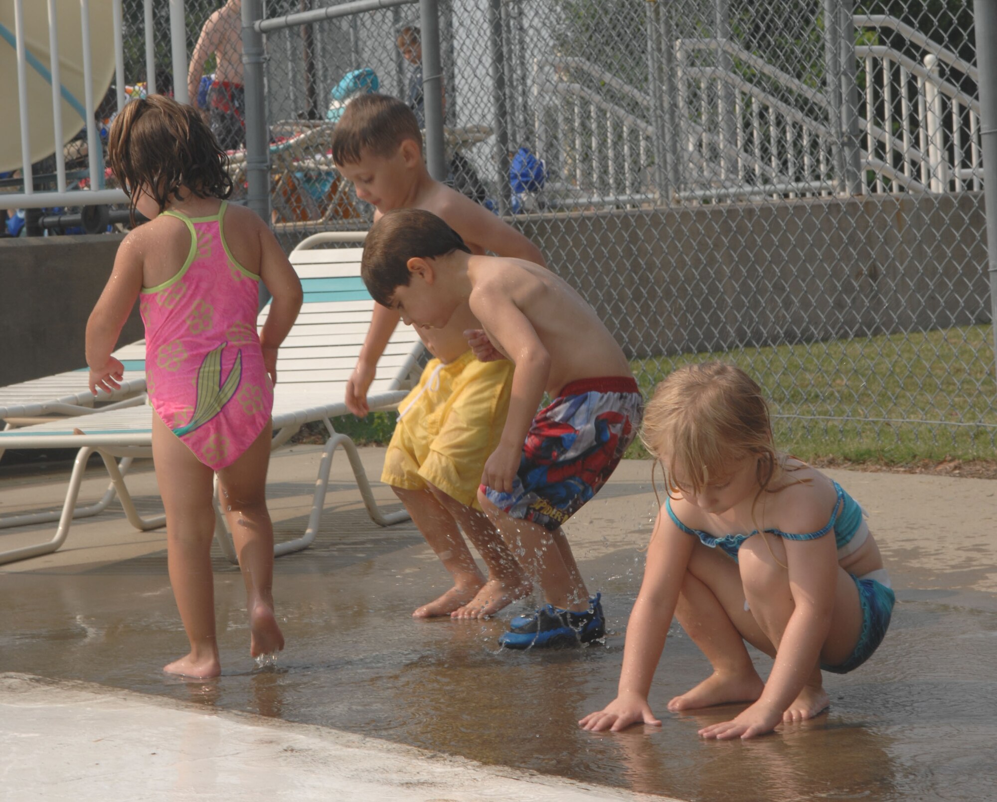 LANGLEY AIR FORCE BASE, Va. -- Preschoolers from the Russ Child Development center take a break from splashing in the Shellbank kiddie pool to concentrate on puddles here June 26. Throughout the summer, children at the Russ Child Development Center take a number of field trips around Langley including walks to the bowling center, library, pool and Eagle Park. (U.S. Air Force Photo/Senior Airman Tabitha Kuykendall)