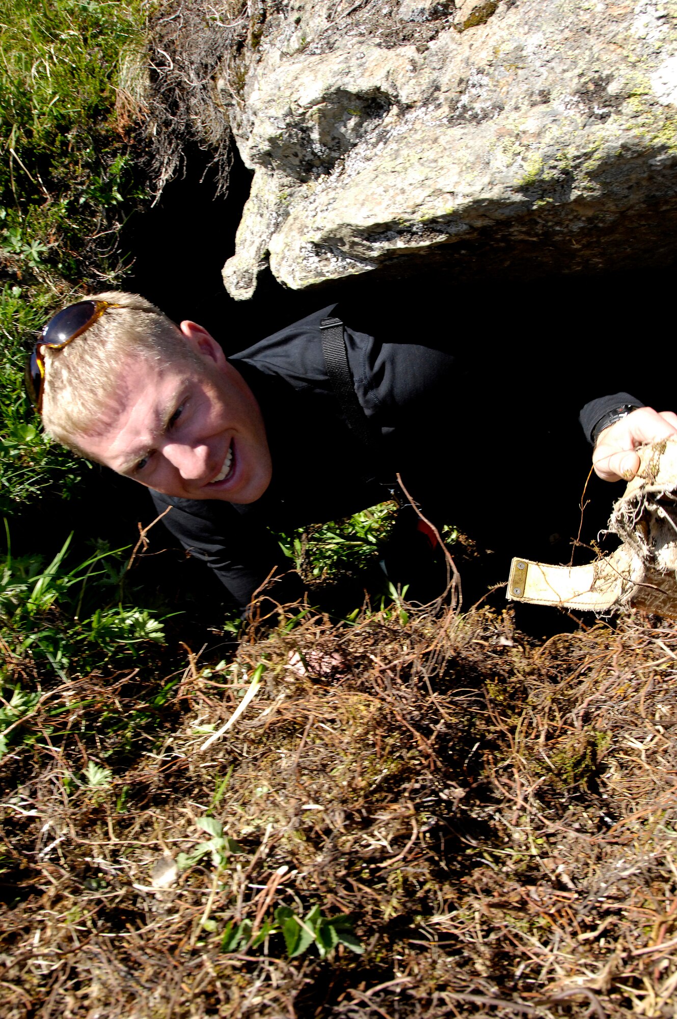 CHUGACH MOUNTAINS, Alaska -- 1st Lt. Luke Buckley climbs out of a brown (grizzly) bear den after recovering a tracking collar that was designed to fall off during winter hibernation. Lieutenant Buckley is a Military Conservation Agent at Elmendorf Air Force Base, Alaska. He volunteered to help Alaska Department of Fish and Game biologists retrieve the collars. The bear tracking study, conducted by the ADFG, was funded by the Department of Defense to monitor the movements of brown bears on Elmendorf and neighboring Fort Richardson. On June 28, three teams of three agents were flown into the mountains with radio trackers and located the collars in the dens. (RELEASED) U.S. Air Force photo by Tech. Sgt. Keith Brown