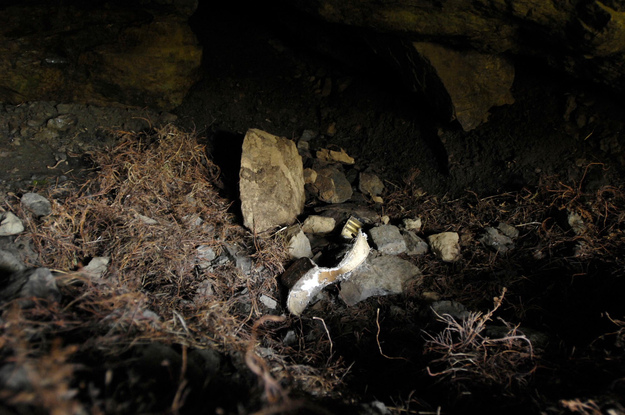 CHUGACH MOUNTAINS, Alaska -- A radio tracking collar sits in a brown (grizzly) bear den. The collar was designed to fall off the bear during the winter hibernation. Nine Elmendorf Air Force Base Military Conservation Agents volunteered to help Alaska Department of Fish and Game biologists retrieve the collars. The bear tracking study, conducted by the ADFG, was funded by the Department of Defense to monitor the movements of brown bears on Elmendorf and neighboring Fort Richardson. On June 28, three teams of three agents were flown into the mountains with radio trackers and located the collars in the dens. (RELEASED) U.S. Air Force photo by Tech. Sgt. Keith Brown