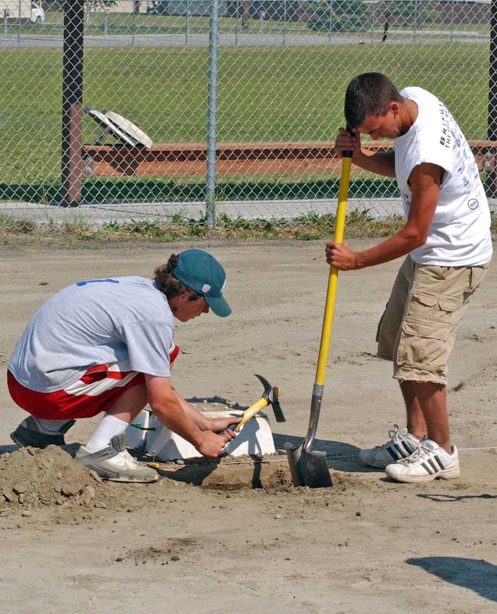 EIELSON AIR FORCE BASE, Alaska--Ken Sample and Dewel Pettway, Interior Girls Softball Association field workers, use a shovel and pick-ax to dig a hole for first base at the Ben Eielson Softball Field June 29. The Raven's softball field recently recieved a complete upgrade which involved removing sharp stones from the field and replacing it with a special in-field mix of dirt. (U.S. Air Force photo by Senior Airman Justin Weaver)