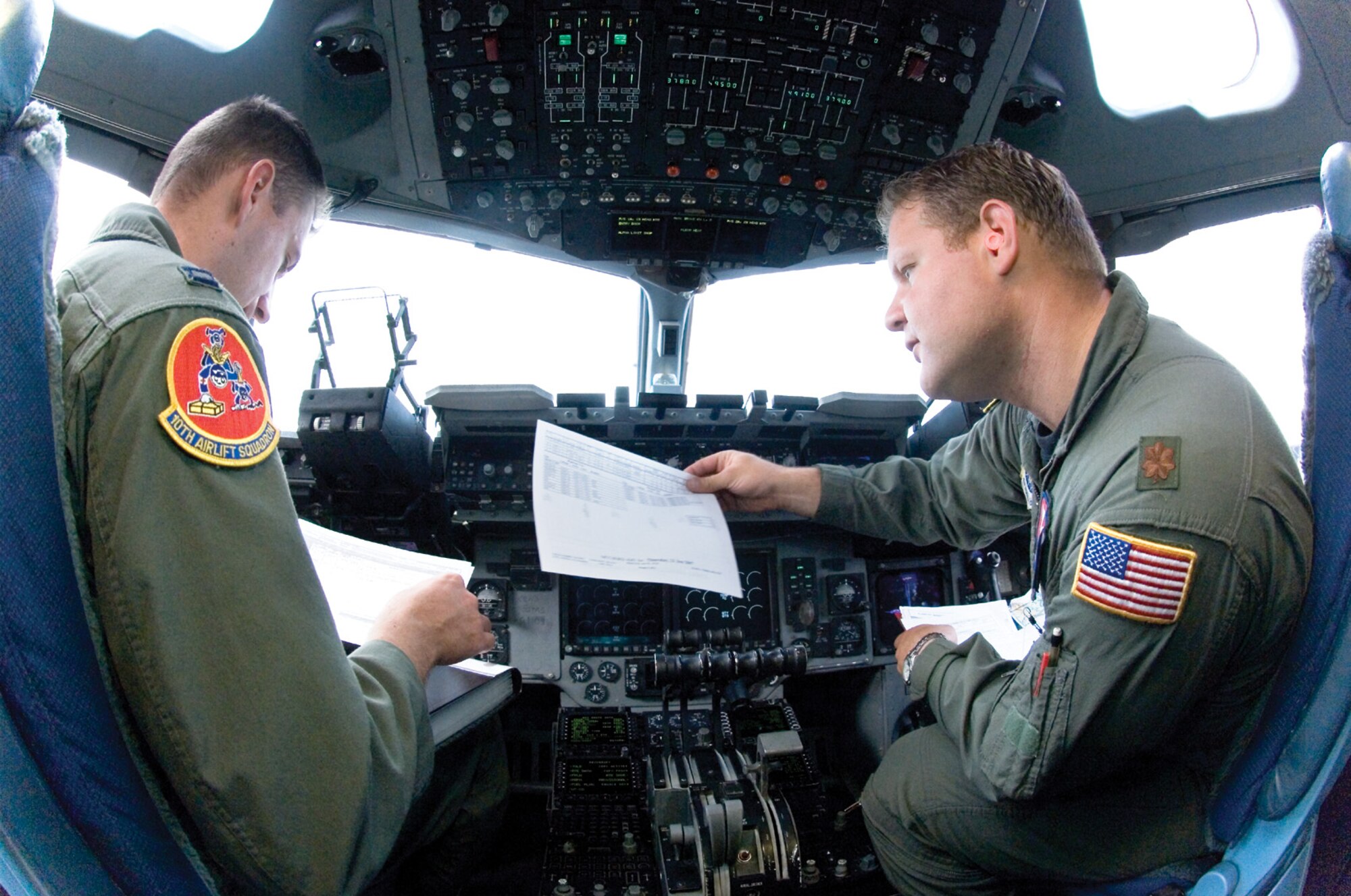MCCHORD AIR FORCE BASE, Wash. -- Capt. Christopher Mazzei, 10th Airlift Squadron, and Maj. Marc Miller, 7th Airlift Squadron, discuss loading coordinates and predicted take-off times during a pre-flight inspection in the cockpit of a C-17 Globemaster III, June 21. (U.S. Air Force Photo/Abner Guzman)