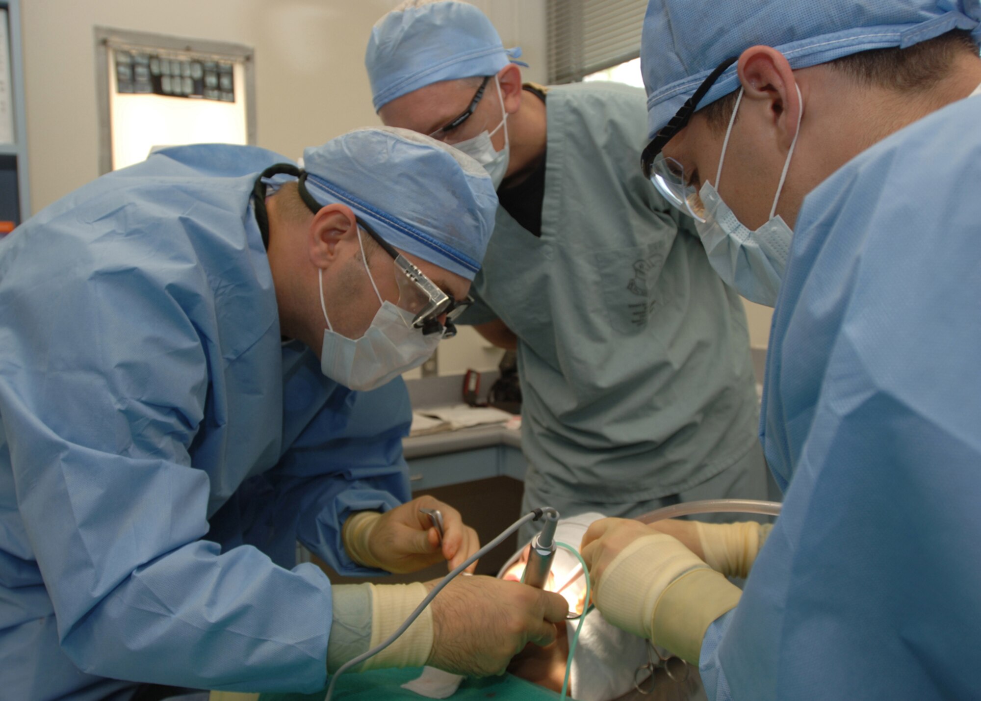 Periodontics resident Maj. (Dr.) Jody Harrison (left), and prosthodontics resident Capt. (Dr.) Cade Salmon (center) , perform a procedure on a patient June 27, at McKown Dental Clinic, Wilford Hall Medical Center, with the assistance of Airman 1st Class Joshua R. Diel (right), dental technician. (U.S. Air Force photo by Cyndy Karras)
