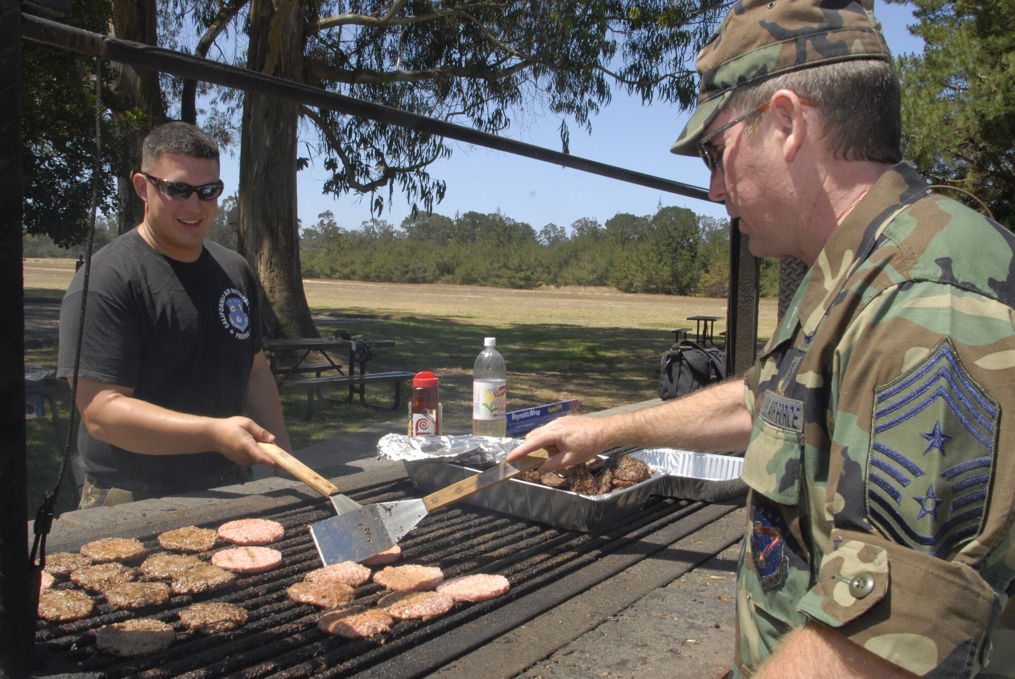 VANDENBERG AIR FORCE BASE, Calif. -- Command Chief Master Sgt. Michael McNiff prepares hamburgers with Senior Airman Andrew Adams for the Junior Reserve Officer Training Corps luncheon at Cocheo Park. The 144th Fighter Wing command chief master sergeant and the sheet metal journeyman with the 144th Maintenance Squadron brought students and dependents of Air and Army National Guard from Fresno, Calif., to Vandenberg to show them the occupational impact and lifestyle demands of their parents, many of whom live nowhere near a military installation. (U.S. Air Force photo/Senior Airman Kristi Emler)