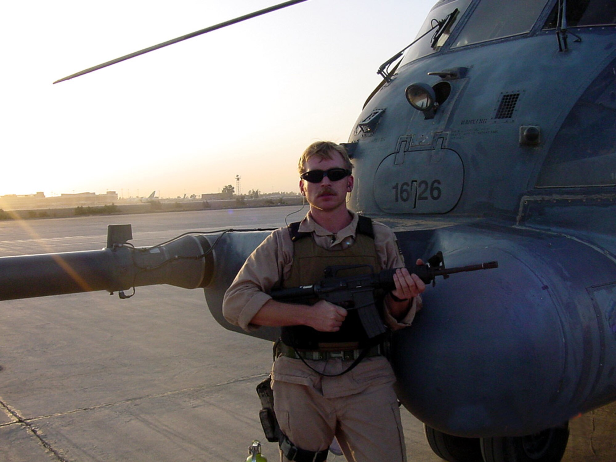 Tech. Sgt. Christian MacKenzie poses stands next to an Air Force special operations MH-53 Pave Low helicopter July 12, 2003, at Baghdad International Airport. Sergeant MacKenzie served as a flight engineer on the helicopter and flew low-level, long-range, undetected missions into enemy territory, day or night, in all kinds of weather, to insert, extract and resupply special operations forces. (Courtesy photo) 