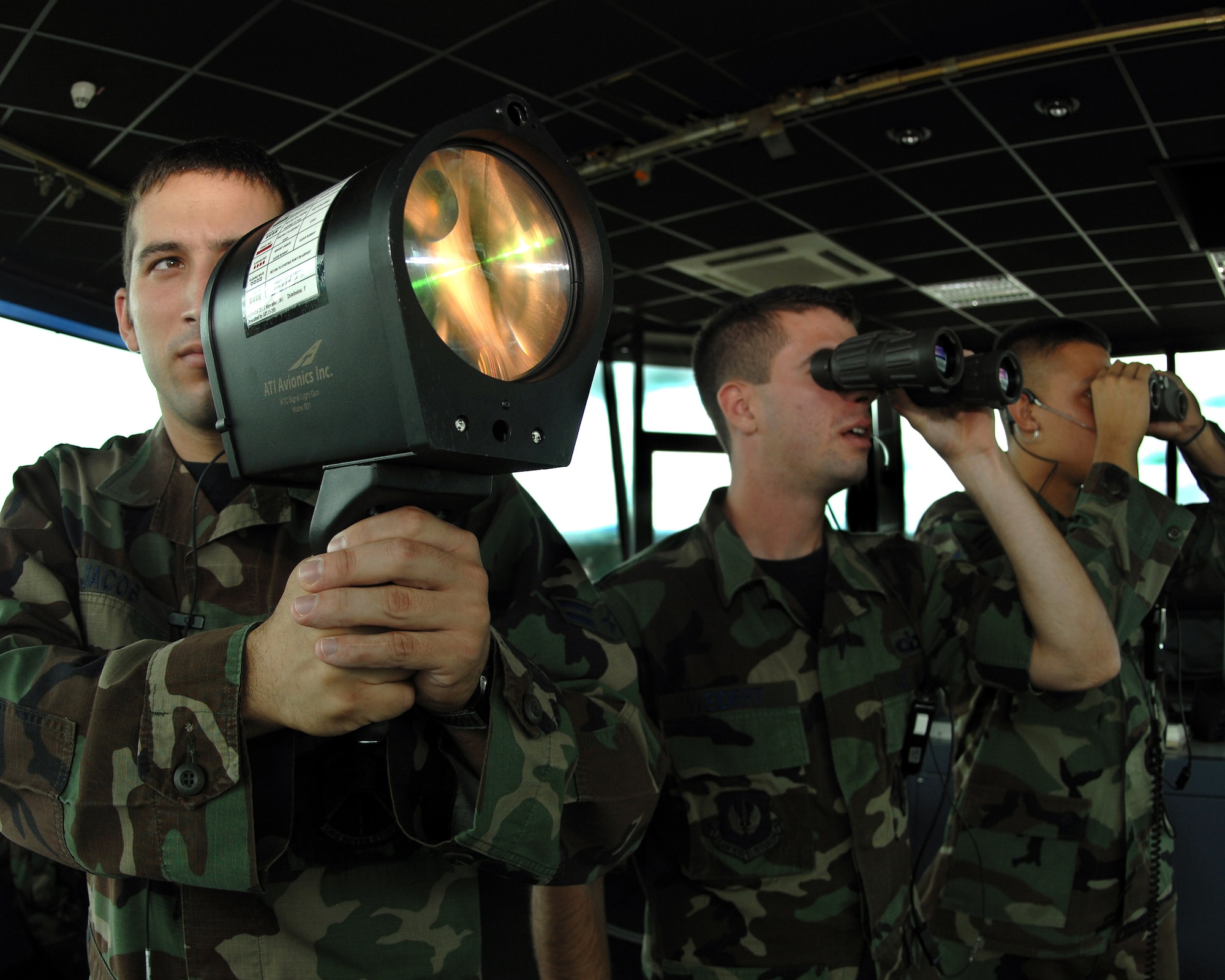 Airman 1st Class Toby Jacob (left to right), Staff Sgt. Mark Weidert and Airman 1st Class Earl Pruett guide inbound aircraft to a safe landing using a light gun June 25 from the control tower at Ramstein Air Base, Germany. The light gun is a vital tool during inclement weather and sometimes is the only way aircraft reach the ground safely. The Airmen are assigned to the 86th Operations Support Squadron. (U.S. Air Force photo/Airman 1st Class Kenny Holston)
